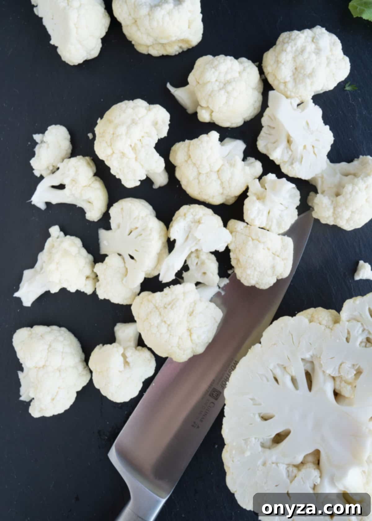 Aromatic Cauliflower Curry Puree 3 Close-up of fresh cauliflower florets, neatly chopped and ready for roasting, on a rustic slate board.