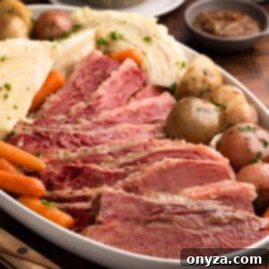 Effortless Slow Cooker Corned Beef and Cabbage 13 Slow cooker corned beef, cabbage, and potatoes on an ivory ceramic platter.