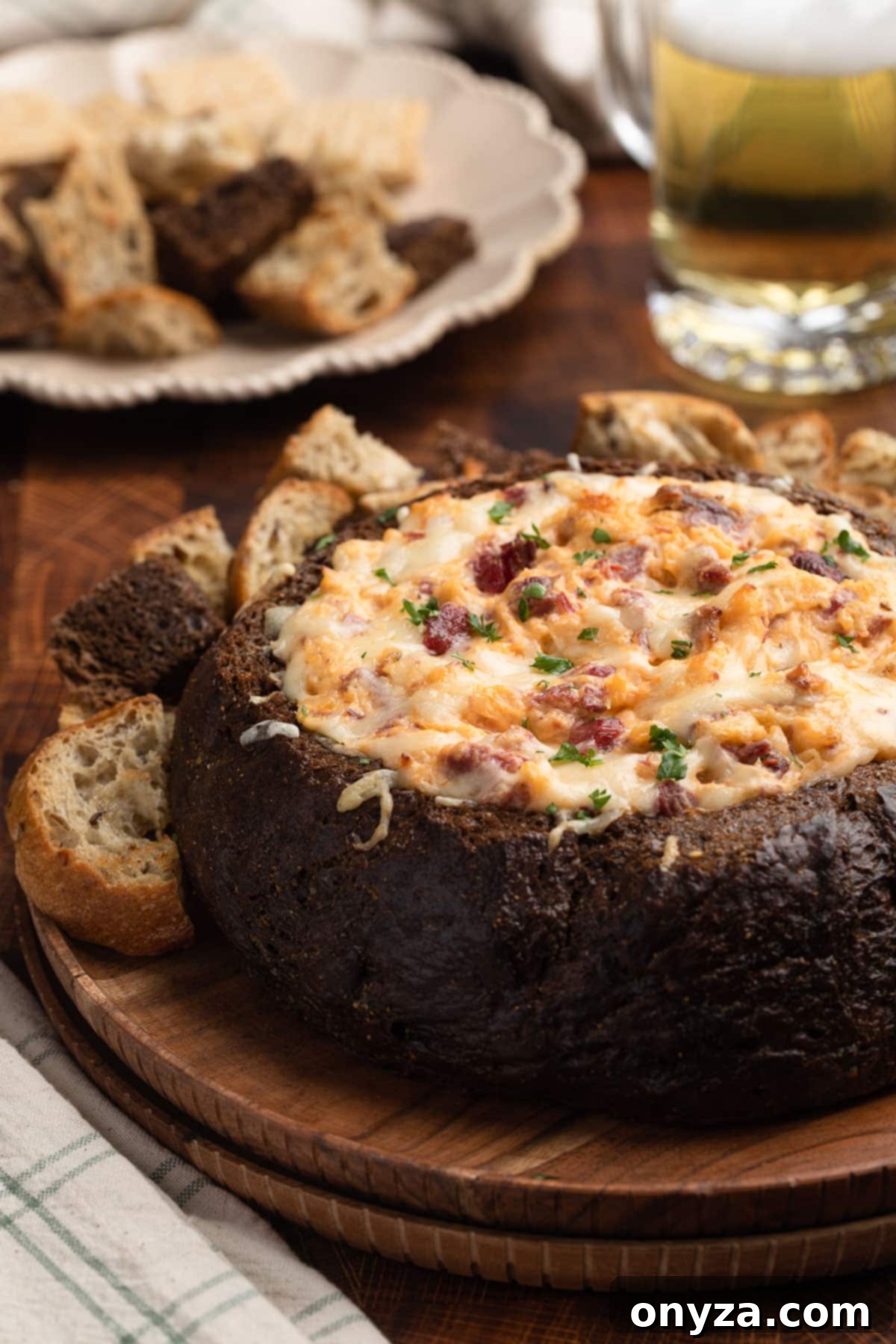 Irresistible Reuben Dip 2 baked reuben dip in a pumpernickel bread bowl on a wood platter with chunks of toasted bread