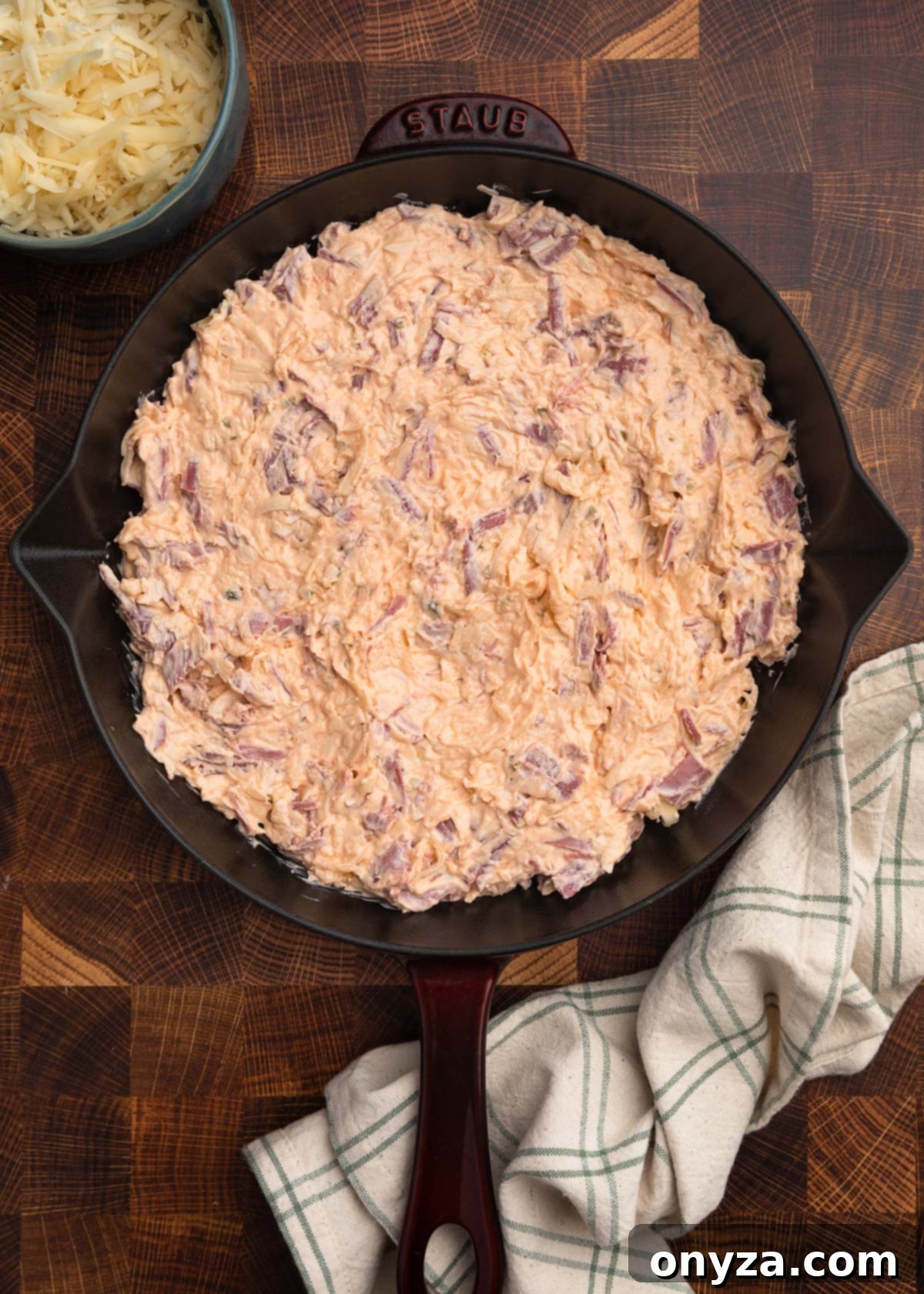Irresistible Reuben Dip 8 overhead photo of unbaked reuben dip in a staub cast iron skillet on a butcher block board