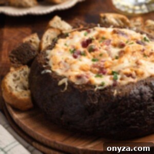 Irresistible Reuben Dip 10 Reuben Dip in a Pumpernickel Bread Bowl on a wooden plate, surrounded by rye and pumpernickel toast dippers
