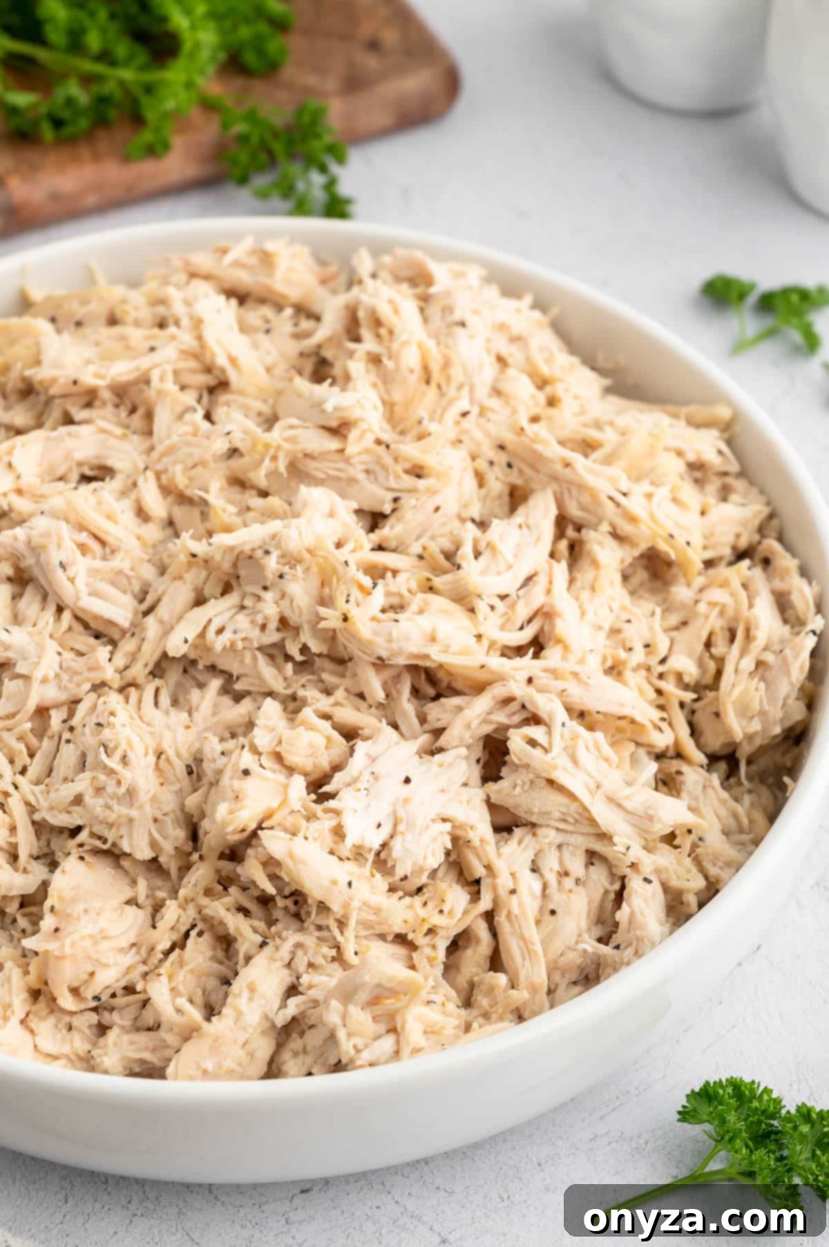 shredded chicken seasoned with black pepper in a white ceramic bowl