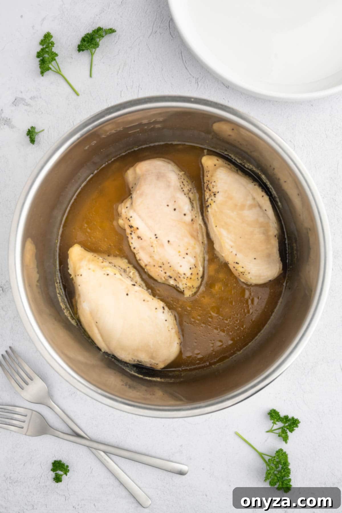 overhead photo of three cooked chicken breasts in a stainless steel Instant Pot insert