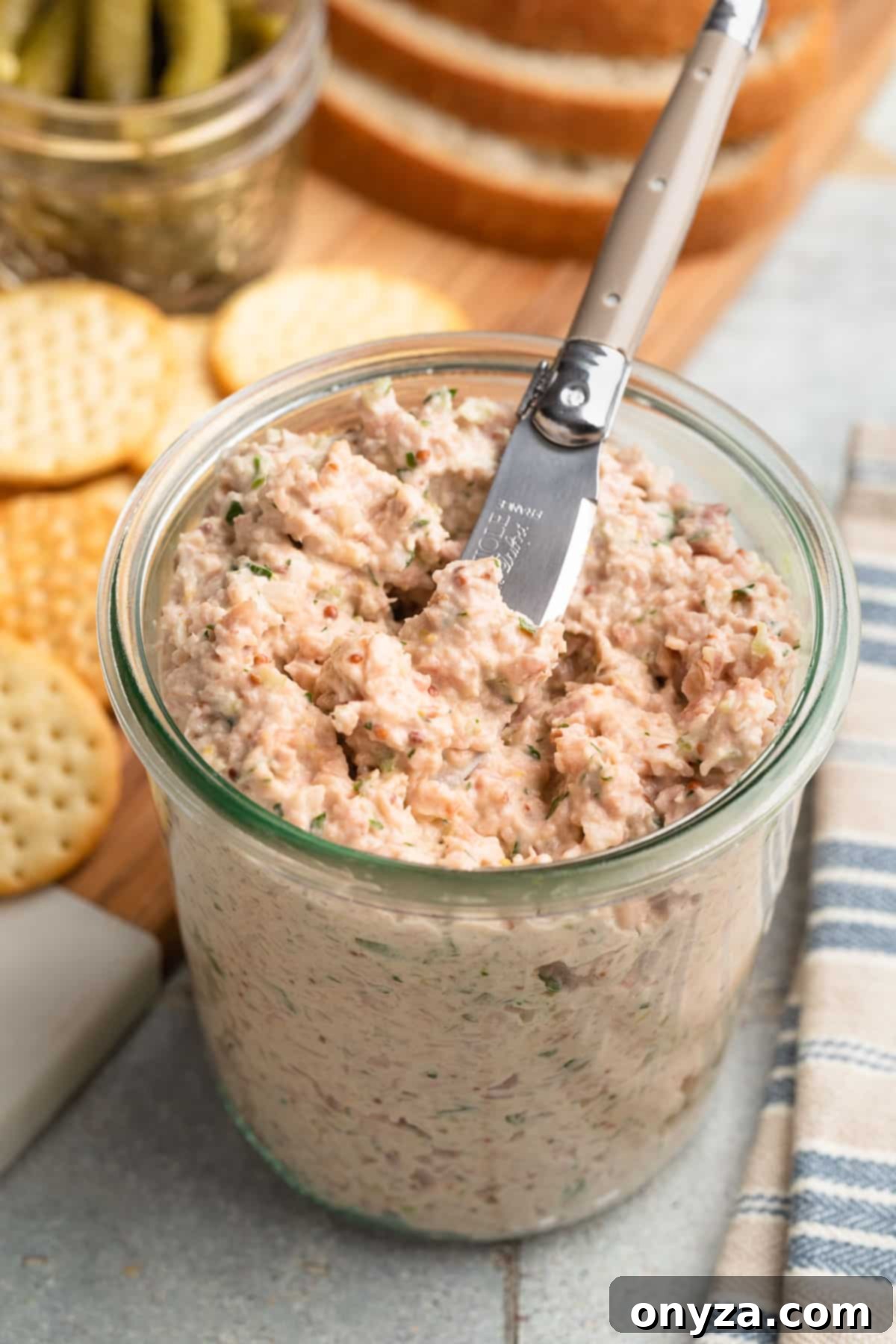 Deviled ham spread presented in a stylish glass jar with a small spreader, ready to be enjoyed.