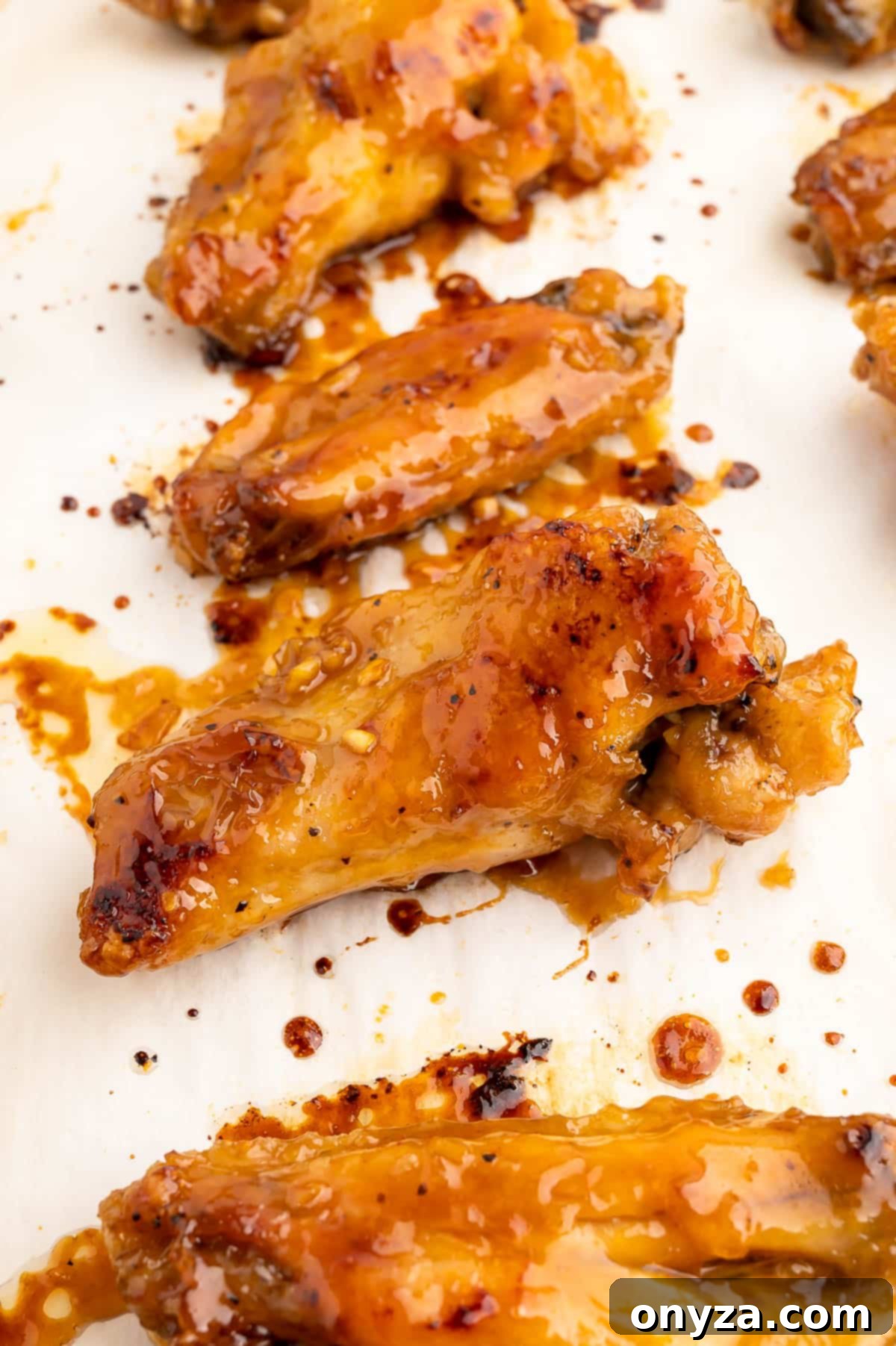 baked chicken wings with honey garlic glaze on a parchment lined baking sheet