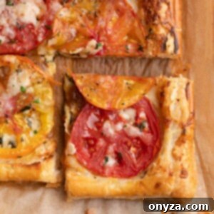 Flaky Tomato Tart 13 closeup of a sliced puff pastry tomato tart on parchment paper