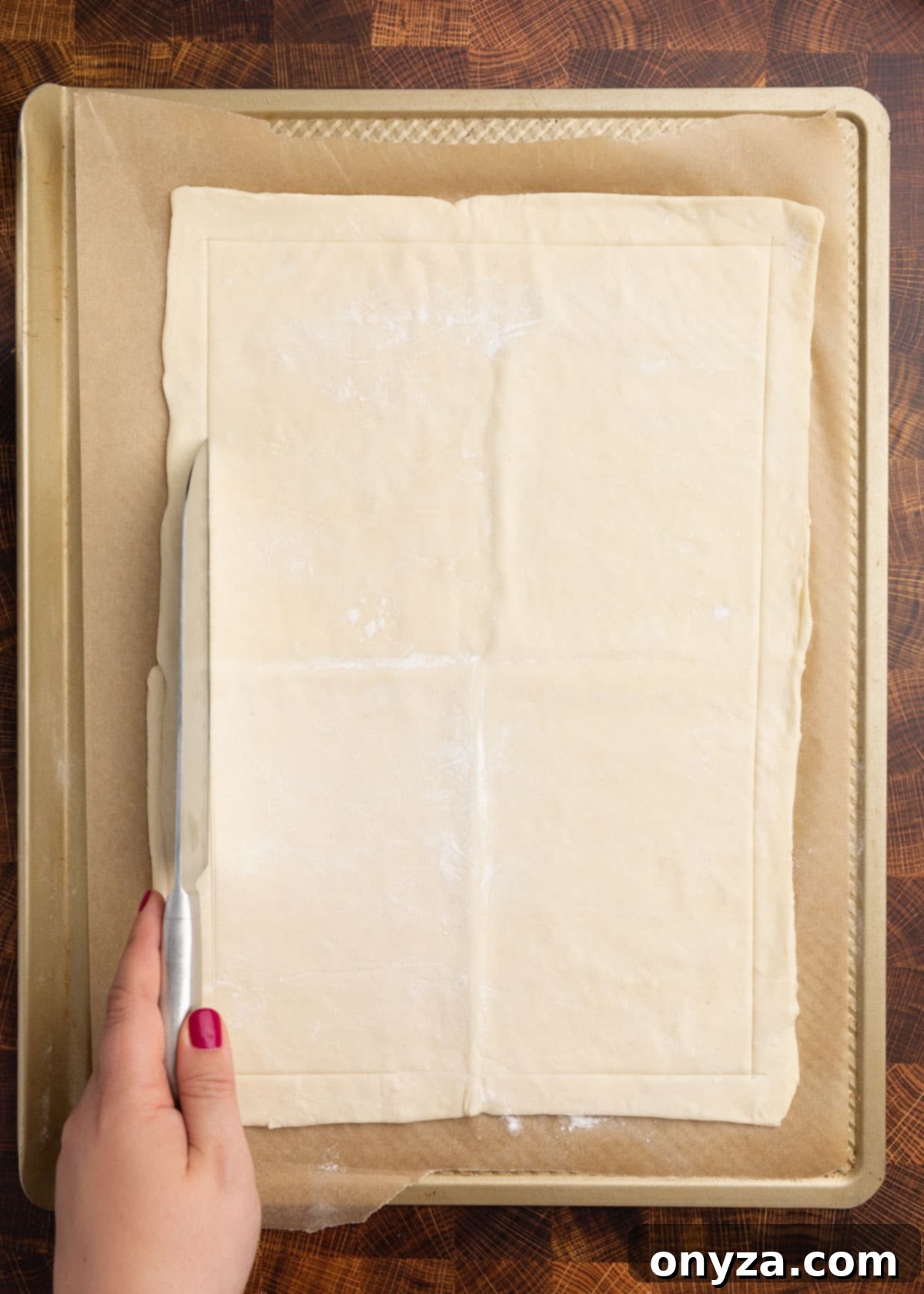 Flaky Tomato Tart 5 overhead photo of puff pastry on a parchment lined baking sheet with a border being scored with a chef's knife