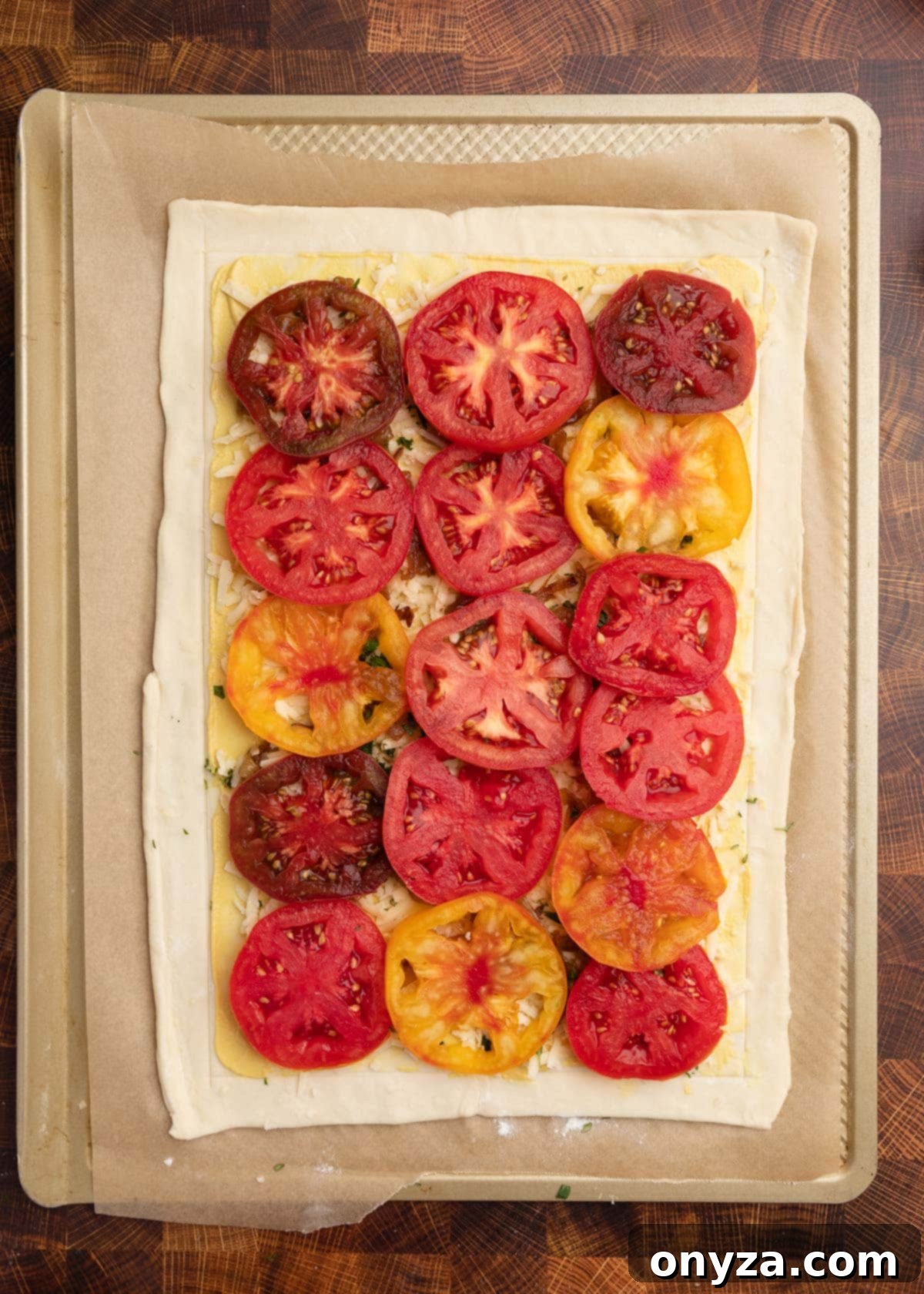 Flaky Tomato Tart 9 overhead photo of an unbaked puff pastry tomato tart on a parchment lined baking sheet