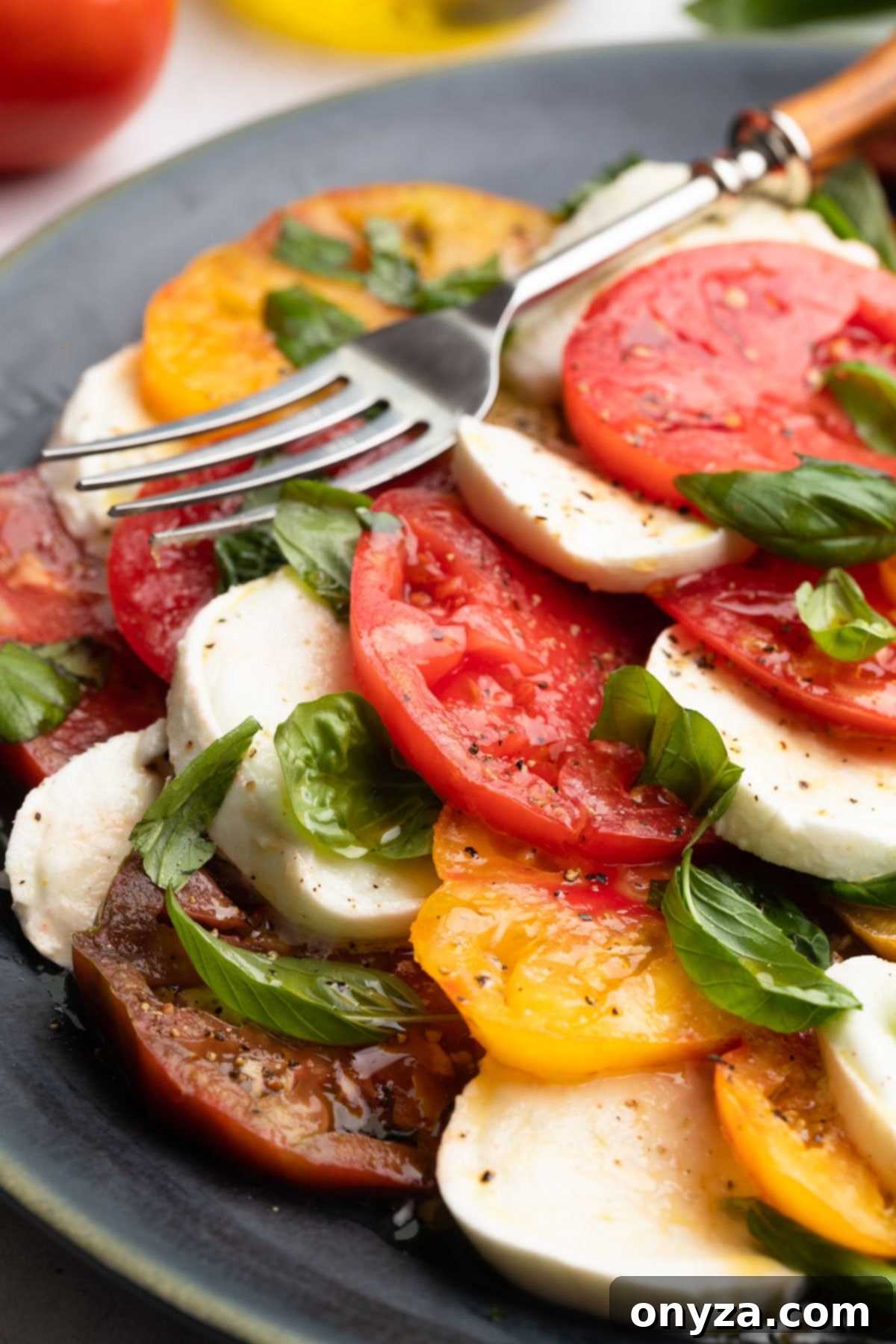 Fresh Caprese Salad 2 caprese salad with a serving fork on a dark gray round platter