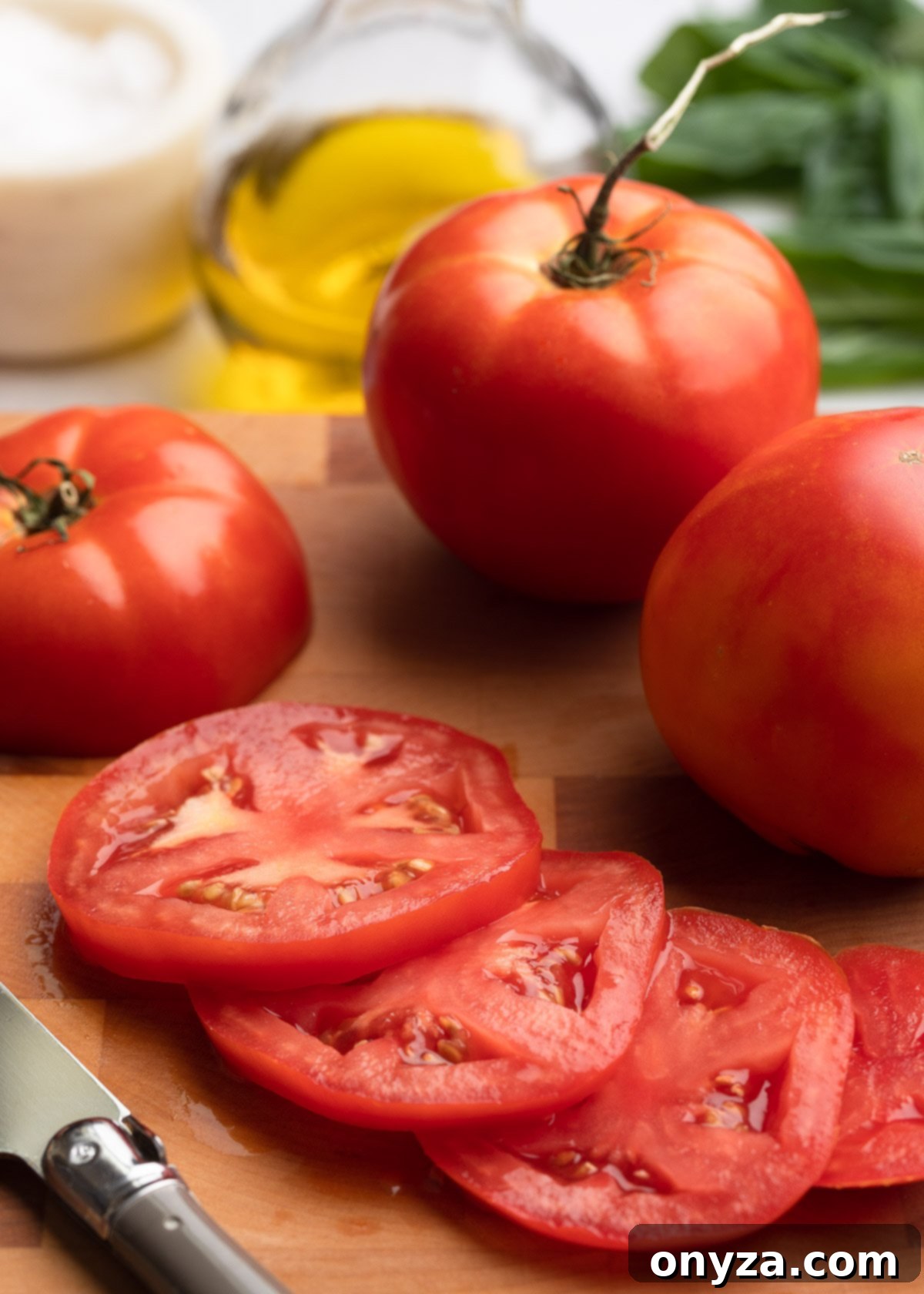 Fresh Caprese Salad 4 sliced tomato on a wooden cutting board next to two whole tomatoes