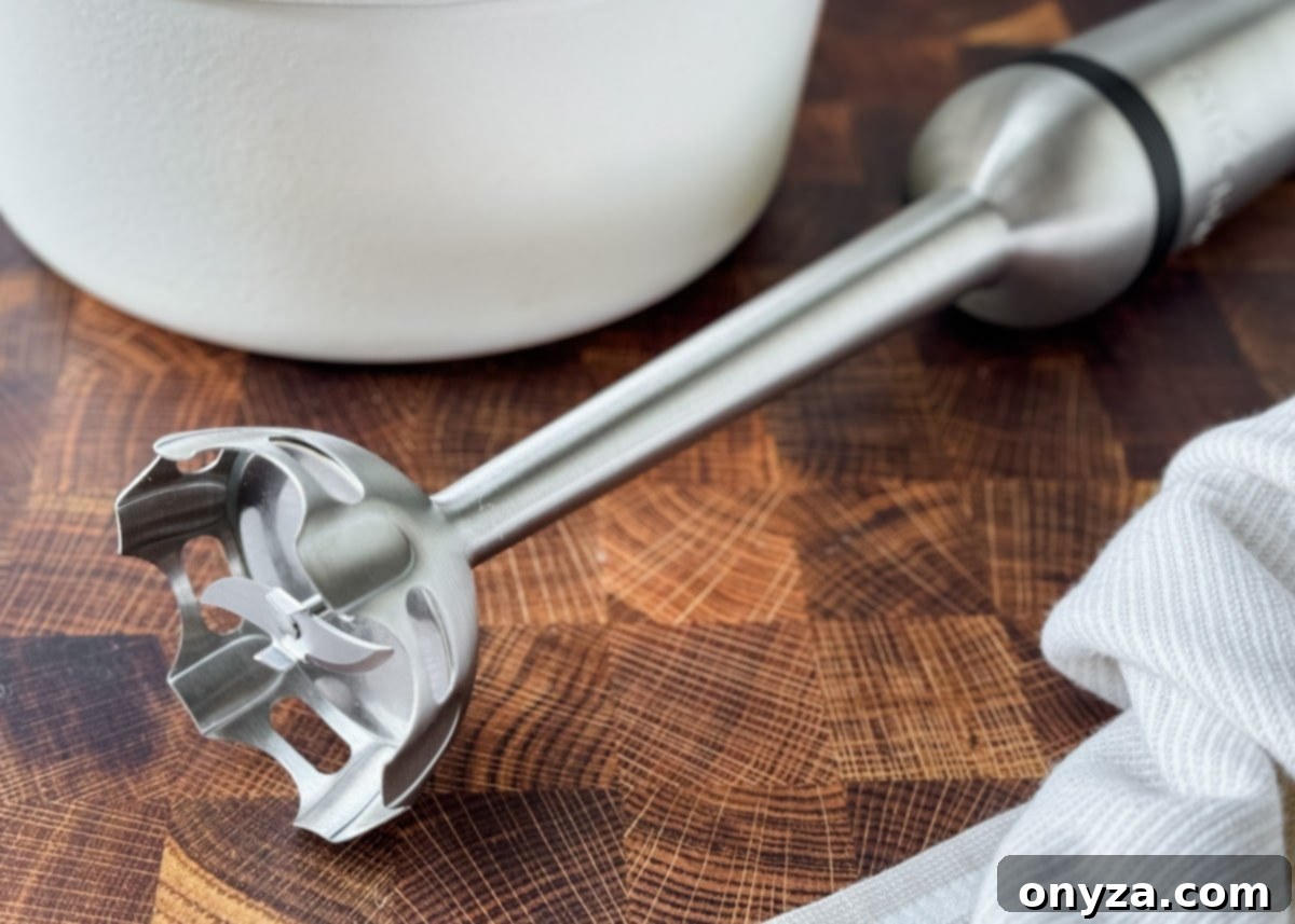 Safely Blend Hot Liquids Without the Mess 4 closeup of an all clad immersion blender on a butcher block counter