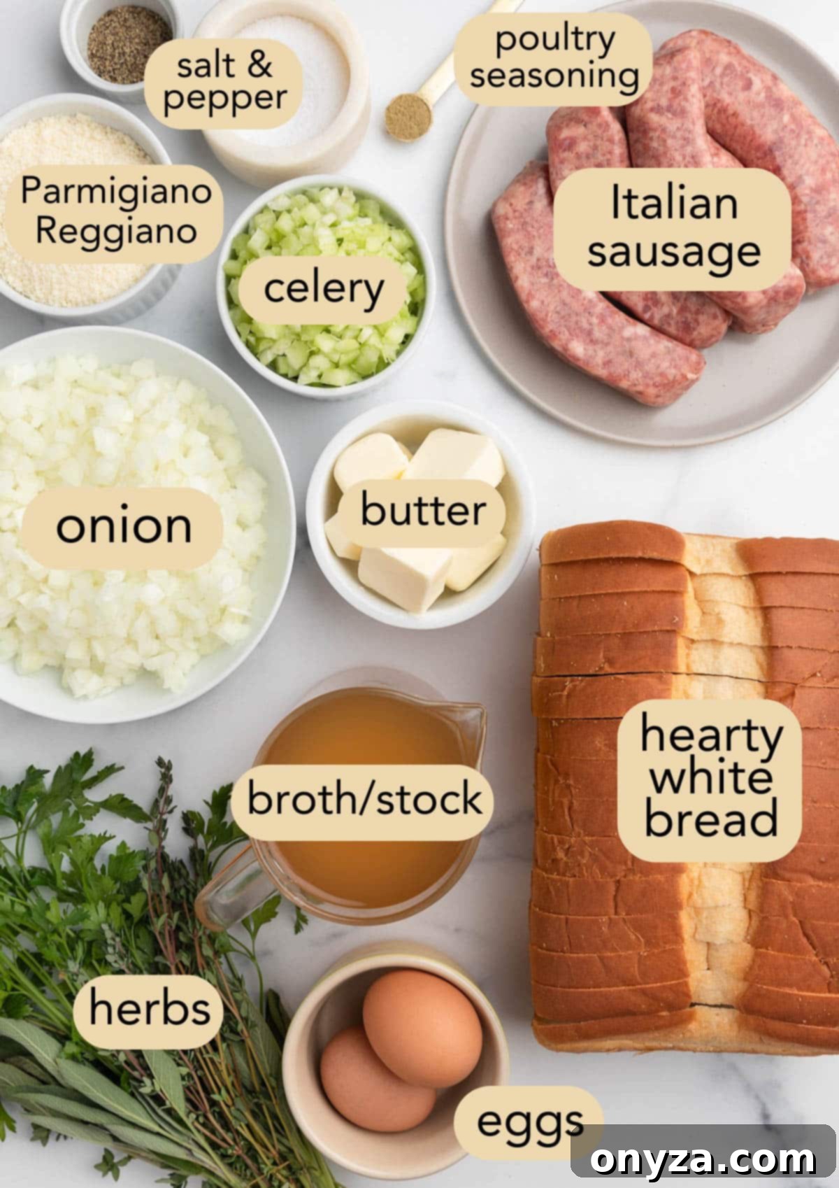 Overhead shot of all ingredients for Italian sausage stuffing laid out in bowls on a white marble board with text labels.