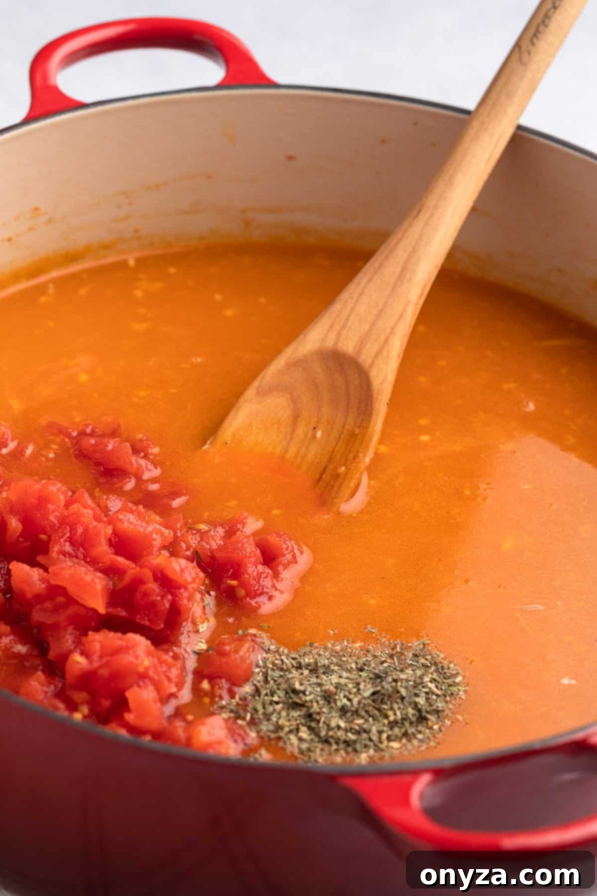 Petite diced Roma tomatoes and fragrant dried Italian seasoning being added to the simmering broth, enriching the flavor profile of the Creamy Sausage Tortellini Soup.