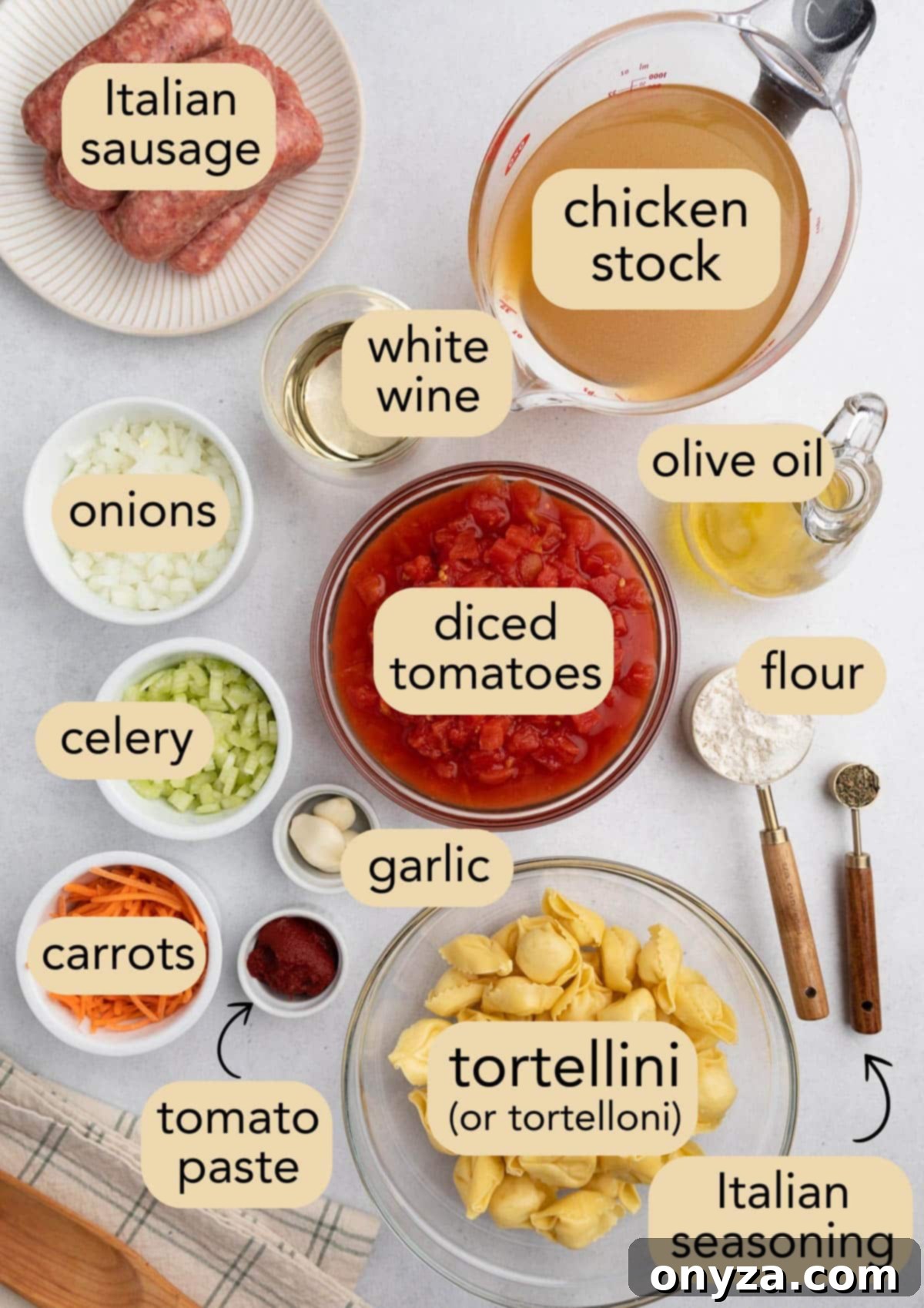 Overhead view of prepped ingredients for Creamy Sausage Tortellini Soup, neatly arranged in bowls and on plates, including chopped vegetables, herbs, and seasonings, on a white background.
