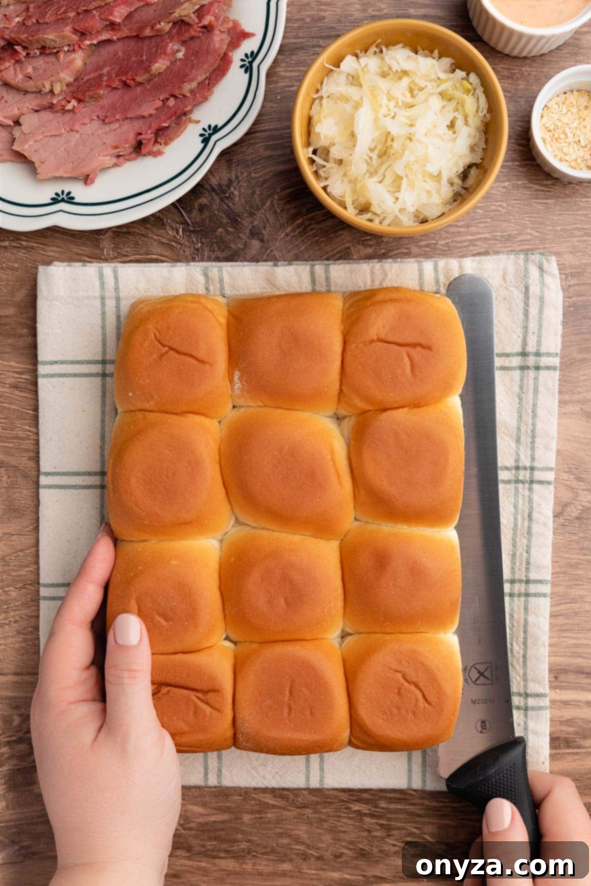 overhead photo of Hawiaan buns being sliced in half with a bread knife on a checked linen napkin