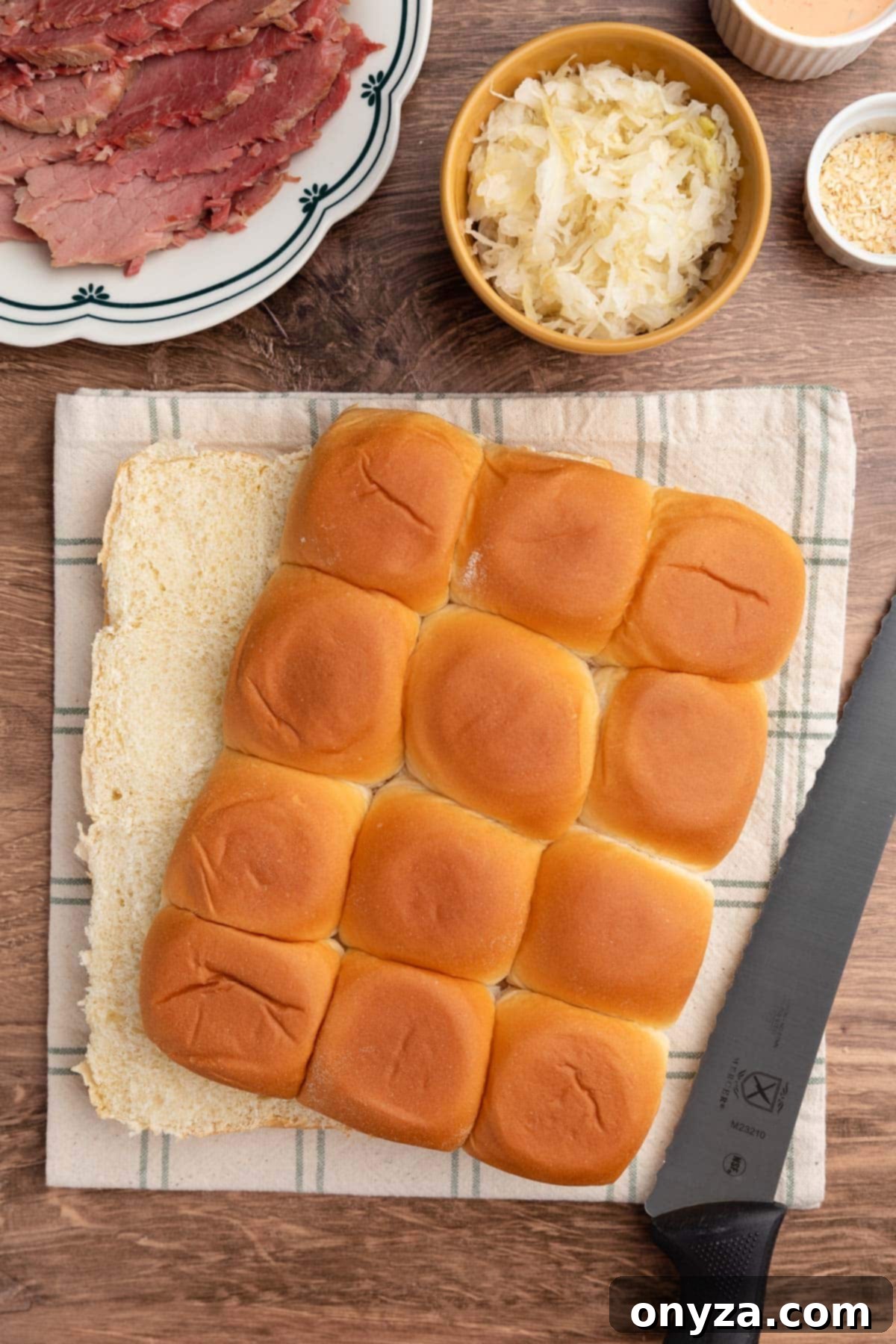 split Hawaiian buns on a linen-checked napkin with a serrated bread knife