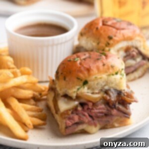 Savory French Dip Sliders 14 french dip sliders on a plate with french fries and a cup of jus