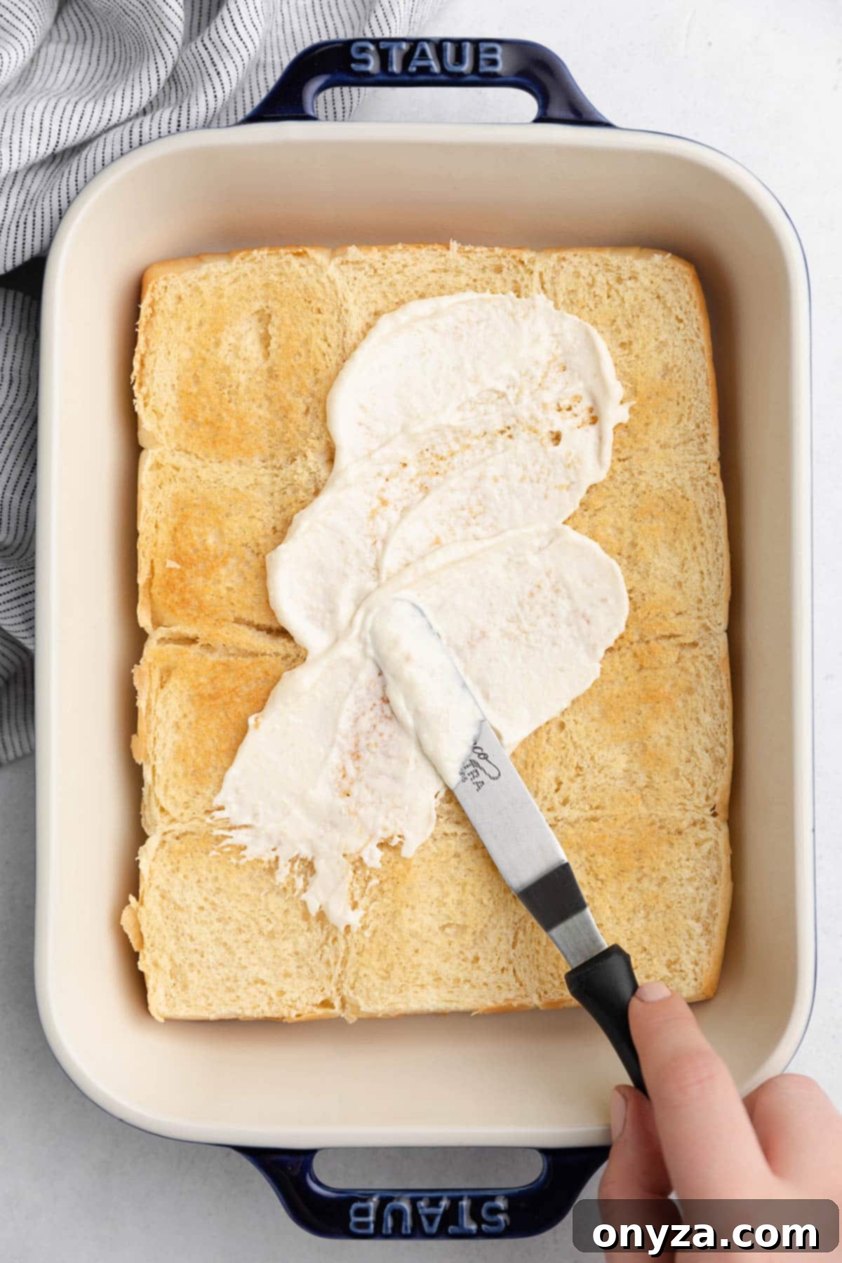 Savory French Dip Sliders 7 spreading horseradish mayo onto toasted slider rolls in a rectangular baking dish with an offset spatula