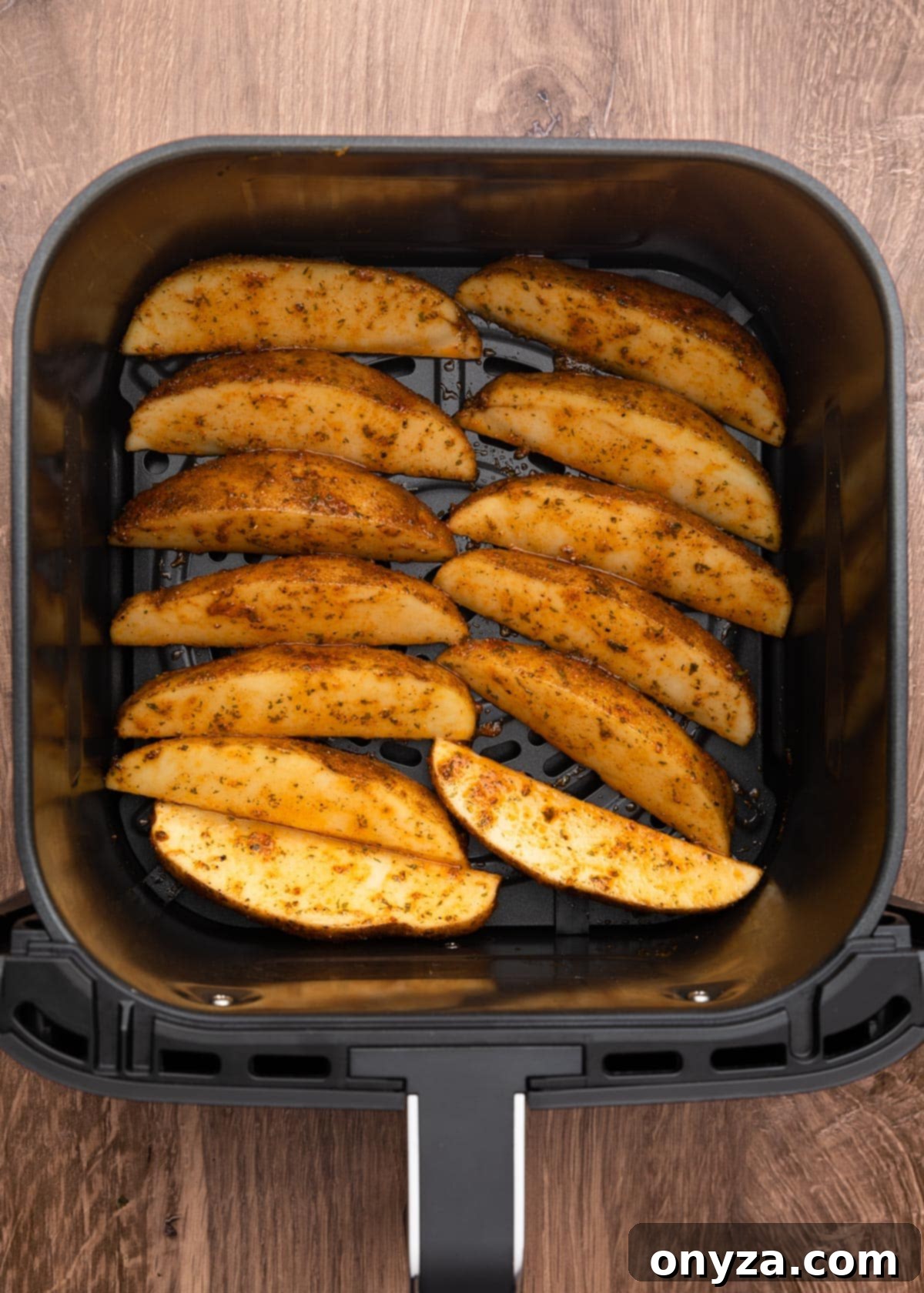 uncooked seasoned potato wedges in a square air fryer basket