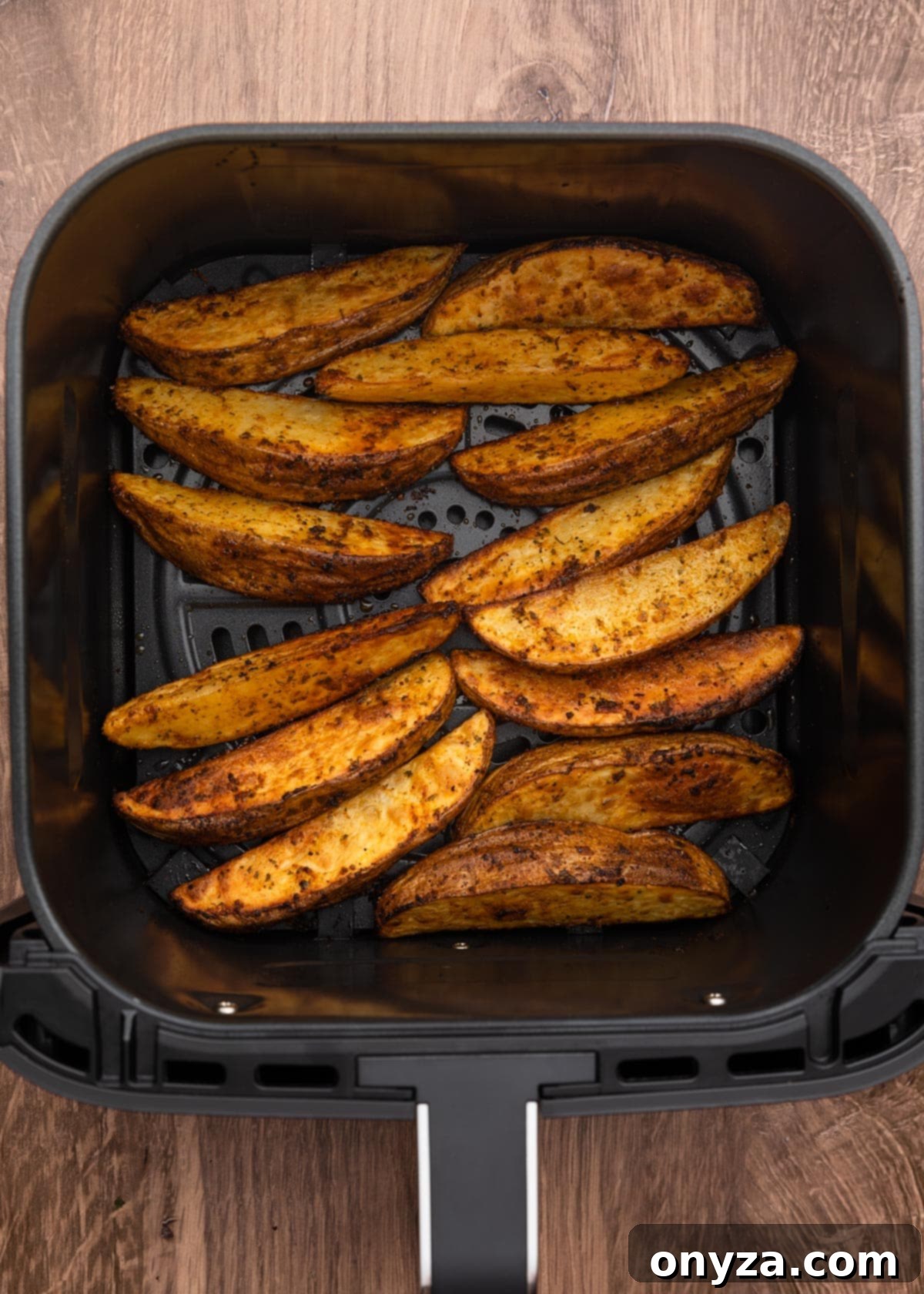 cooked seasoned potato wedges in a square air fryer basket