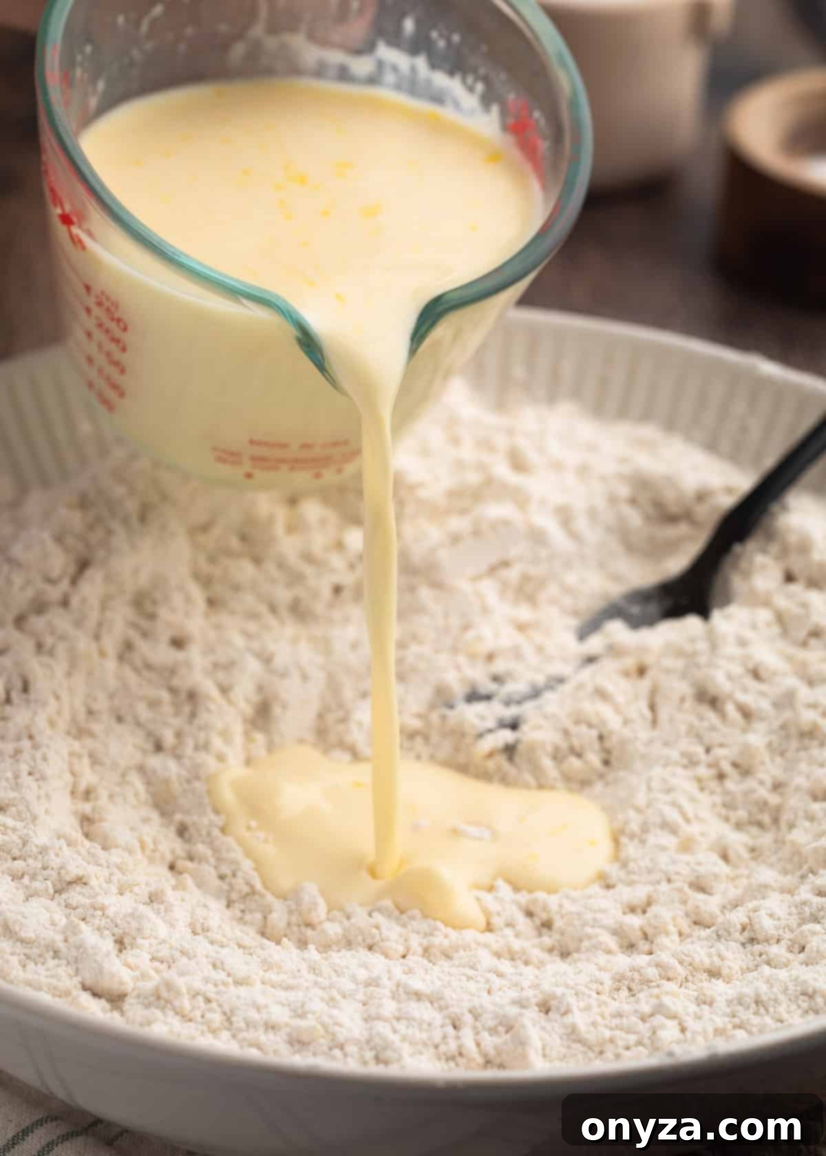 wet ingredients being poured into a bowl of dry ingredients from a glass measuring cup for Irish scones