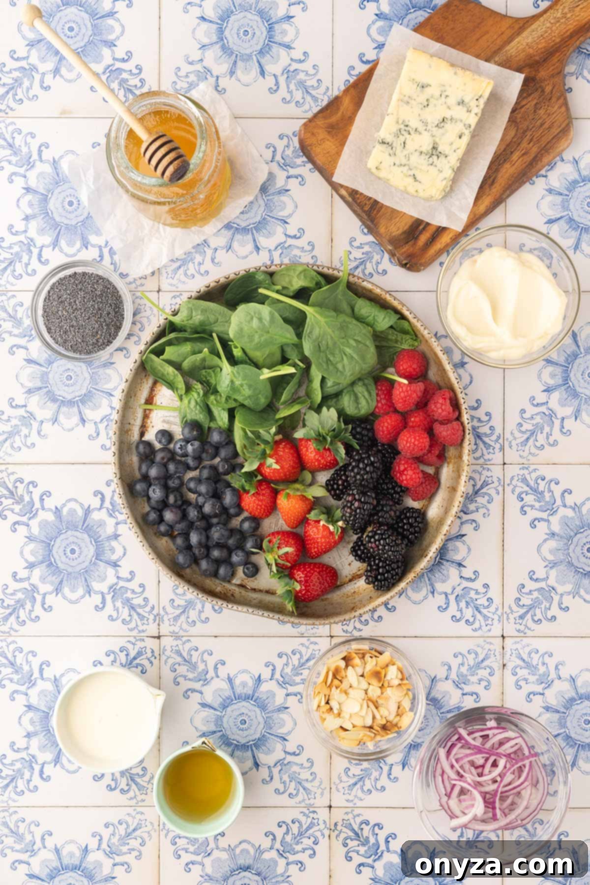 Overhead view of fresh ingredients meticulously laid out on a blue tile board, ready to be transformed into a delicious spinach berry salad.