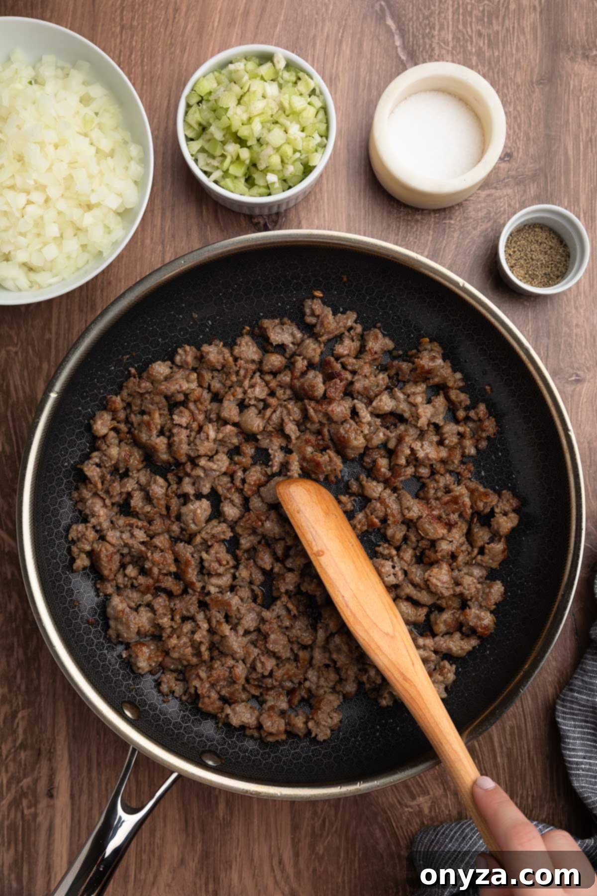 Festive Sausage and Chestnut Stuffing 8 browned Italian sausage crumbles being stirred with a wooden spoon in a skillet