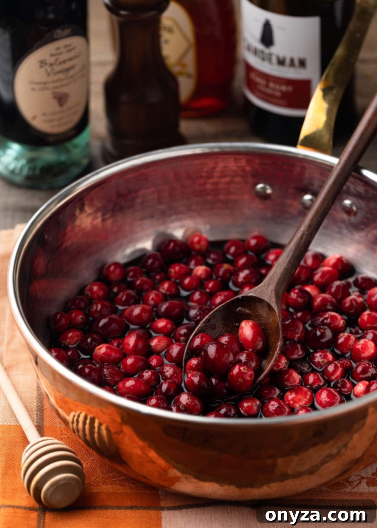 port wine cranberry sauce in a copper saucepan with a wooden spoon before simmering