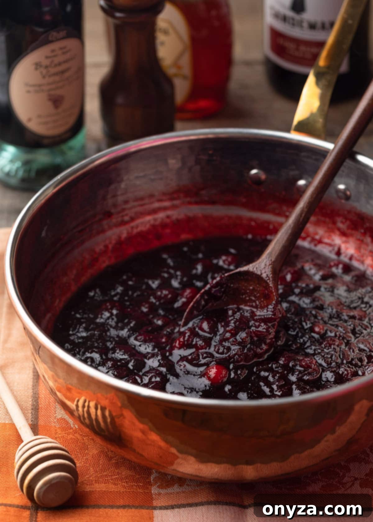 simmered and thickened port wine cranberry sauce in a copper saucepan with a wooden spoon