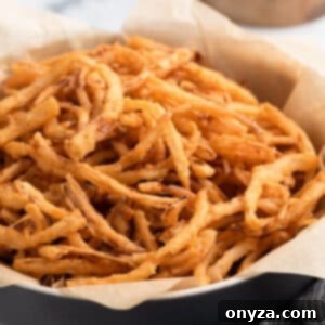 A close-up of a black bowl lined with parchment paper, filled with crispy homemade French fried onions