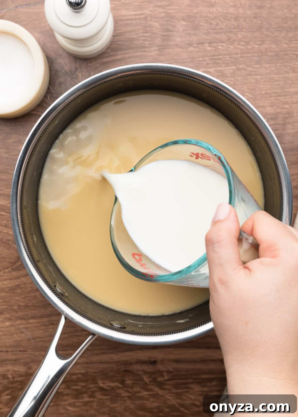 pouring milk from a liquid measuring cup into a pot of condensed cream of chicken soup