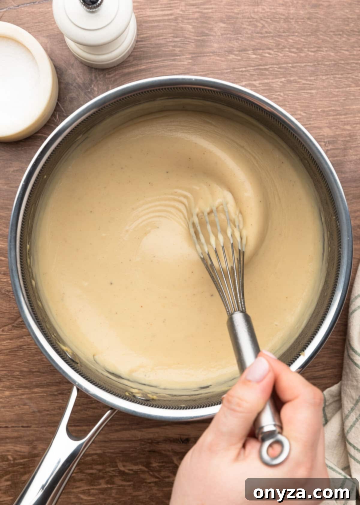 homemade condensed cream of chicken soup being whisked in a pot after cooking to thicken