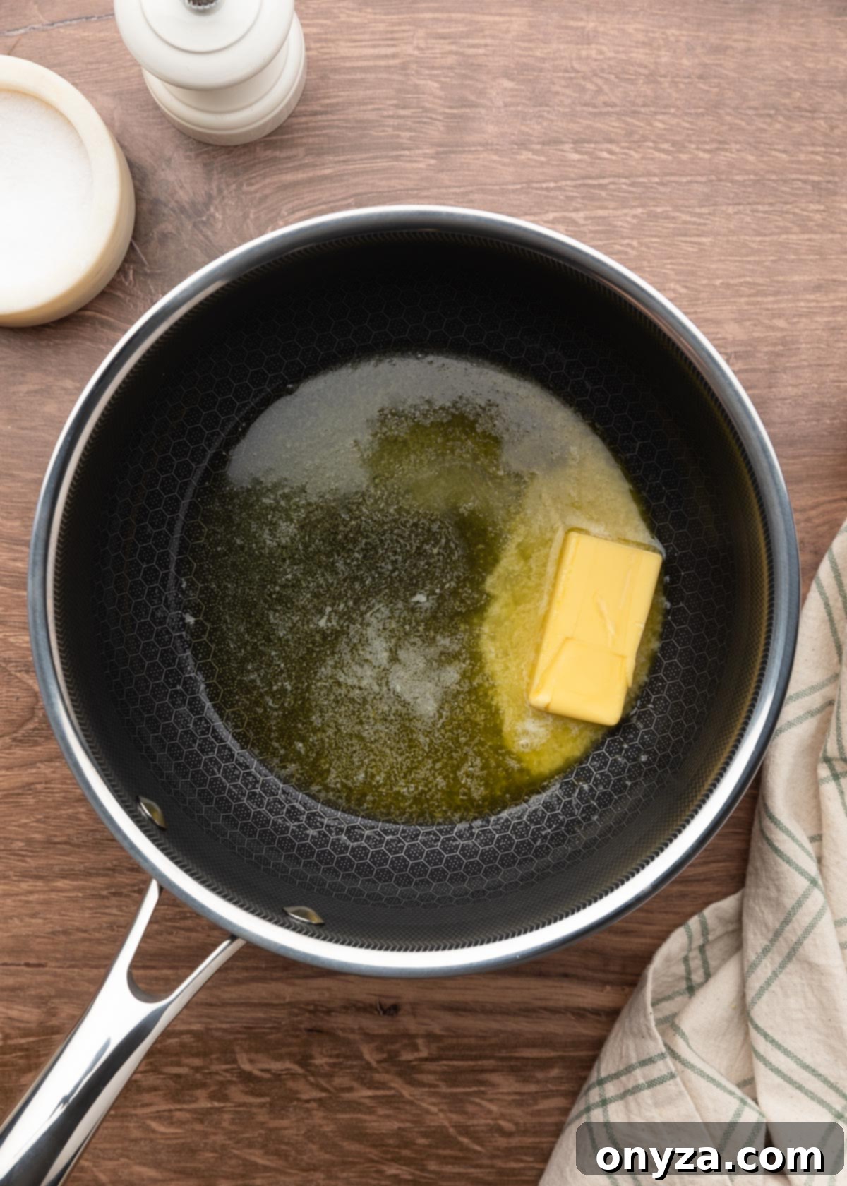 a half stick of butter partially melted in a pot on a wood board