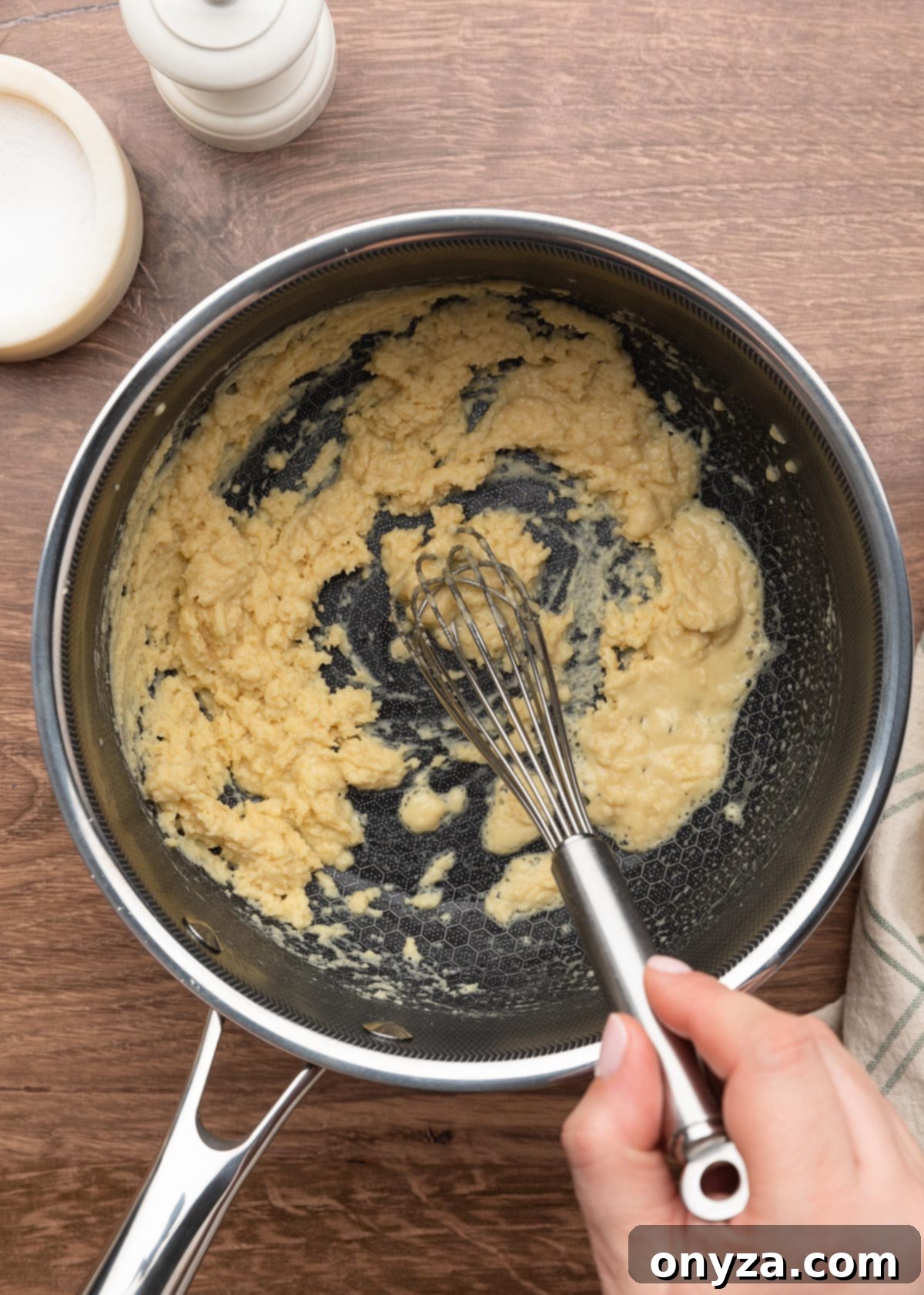 lightly cooked roux being whisked in a pot on a wood board