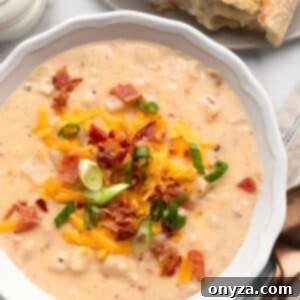 A vibrant overhead image of a single bowl of Crockpot Hashbrown Potato Soup, garnished with fresh herbs and bacon, ready to be served.