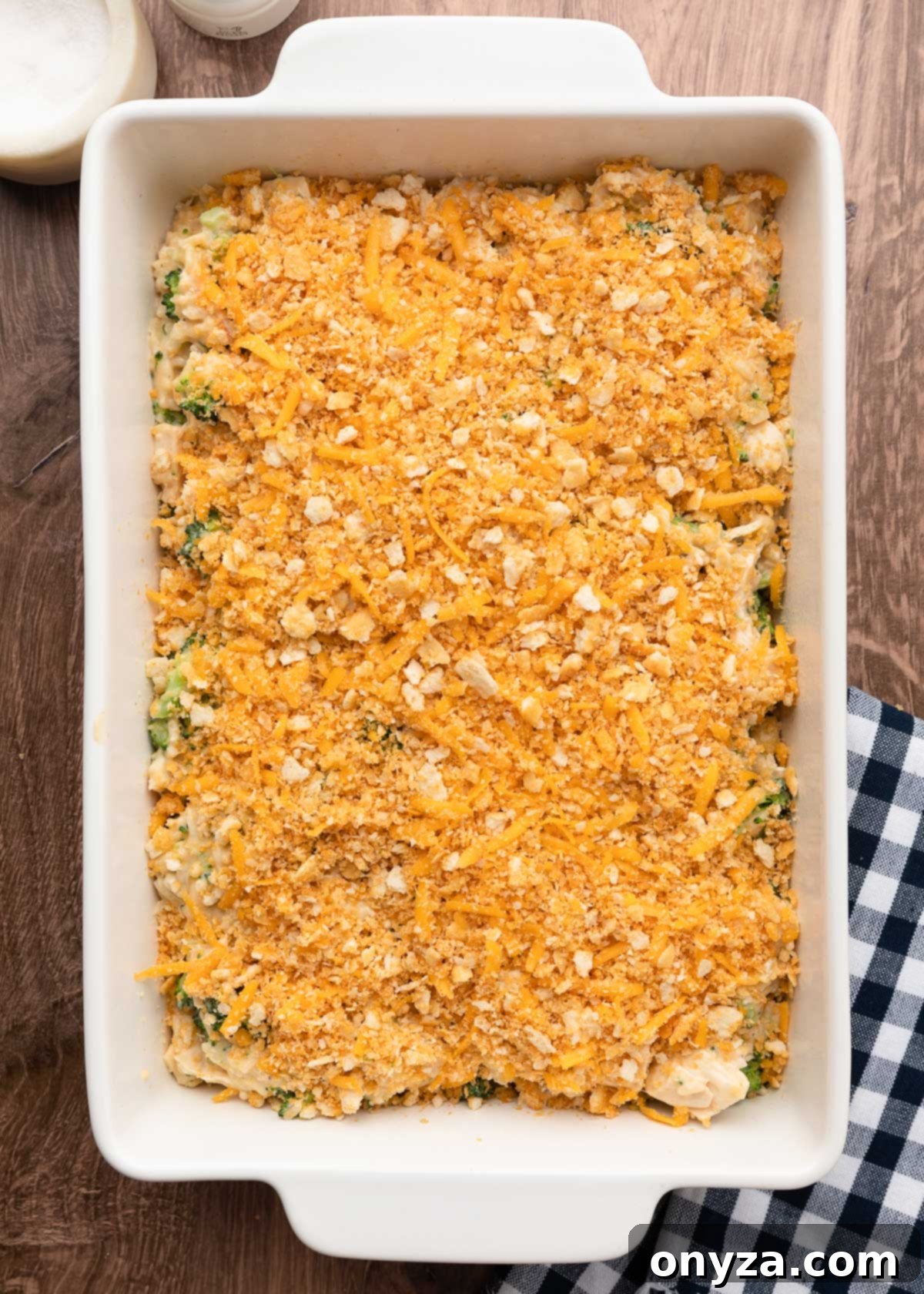 Overhead view of an unbaked cracker crumb topped chicken broccoli rice casserole in a white baking dish, perfectly assembled and ready for the oven.