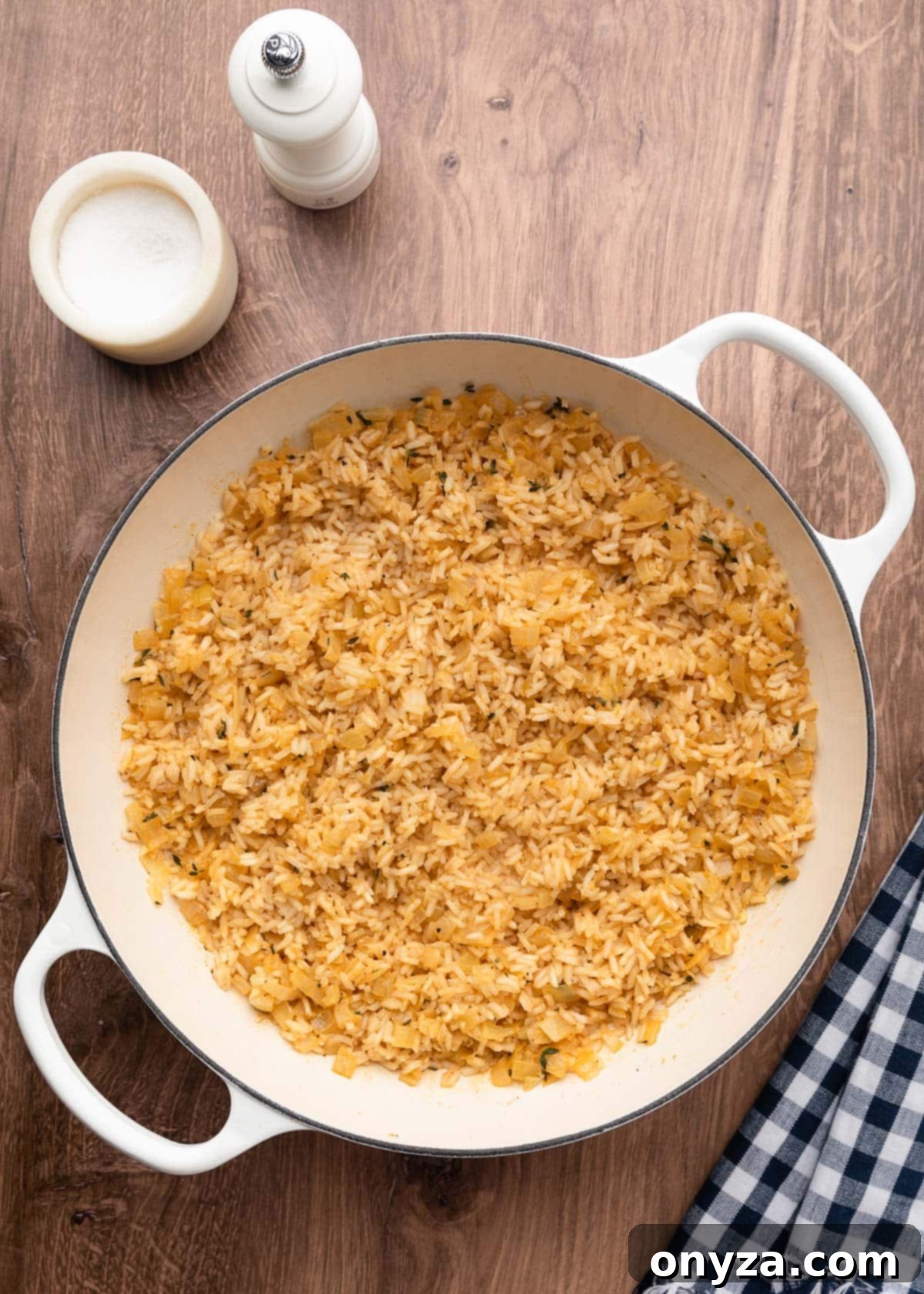 Overhead shot of fluffy, cooked, seasoned long-grain rice in a white enameled cast iron pot, ready for the next step of the casserole.
