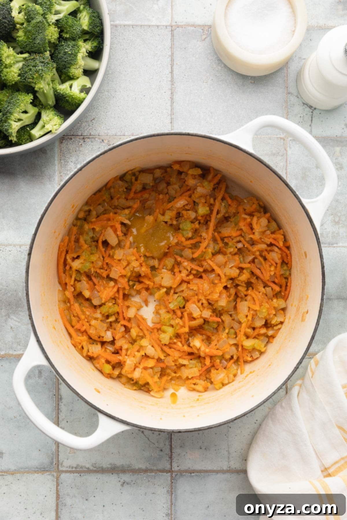 sauteed mirepoix coated with flour with a dollop of roasted chicken base in a white enameled cast iron dutch oven
