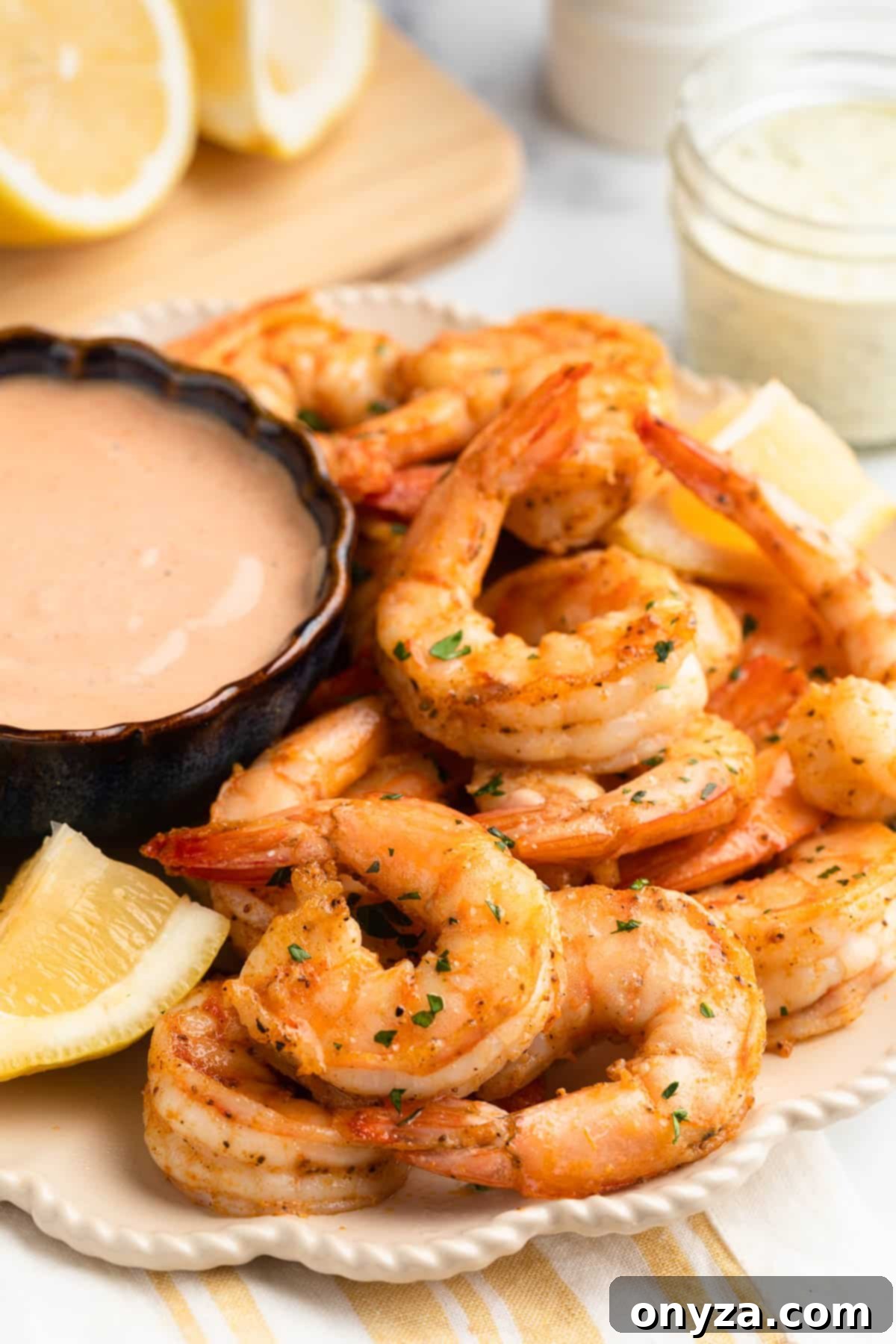 Crispy Air Fryer Shrimp 2 air fryer shrimp on an ivory scalloped plate with lemon wedges and a bowl of dipping sauce