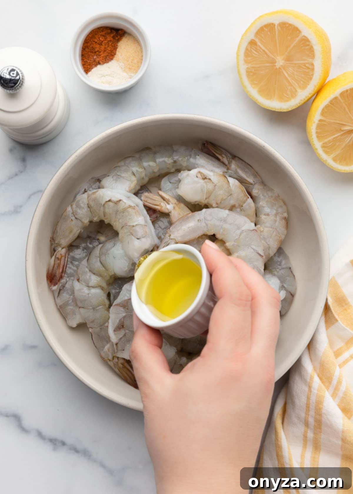 Crispy Air Fryer Shrimp 5 pouring olive oil into a bowl of raw shrimp from a tiny white ramekin