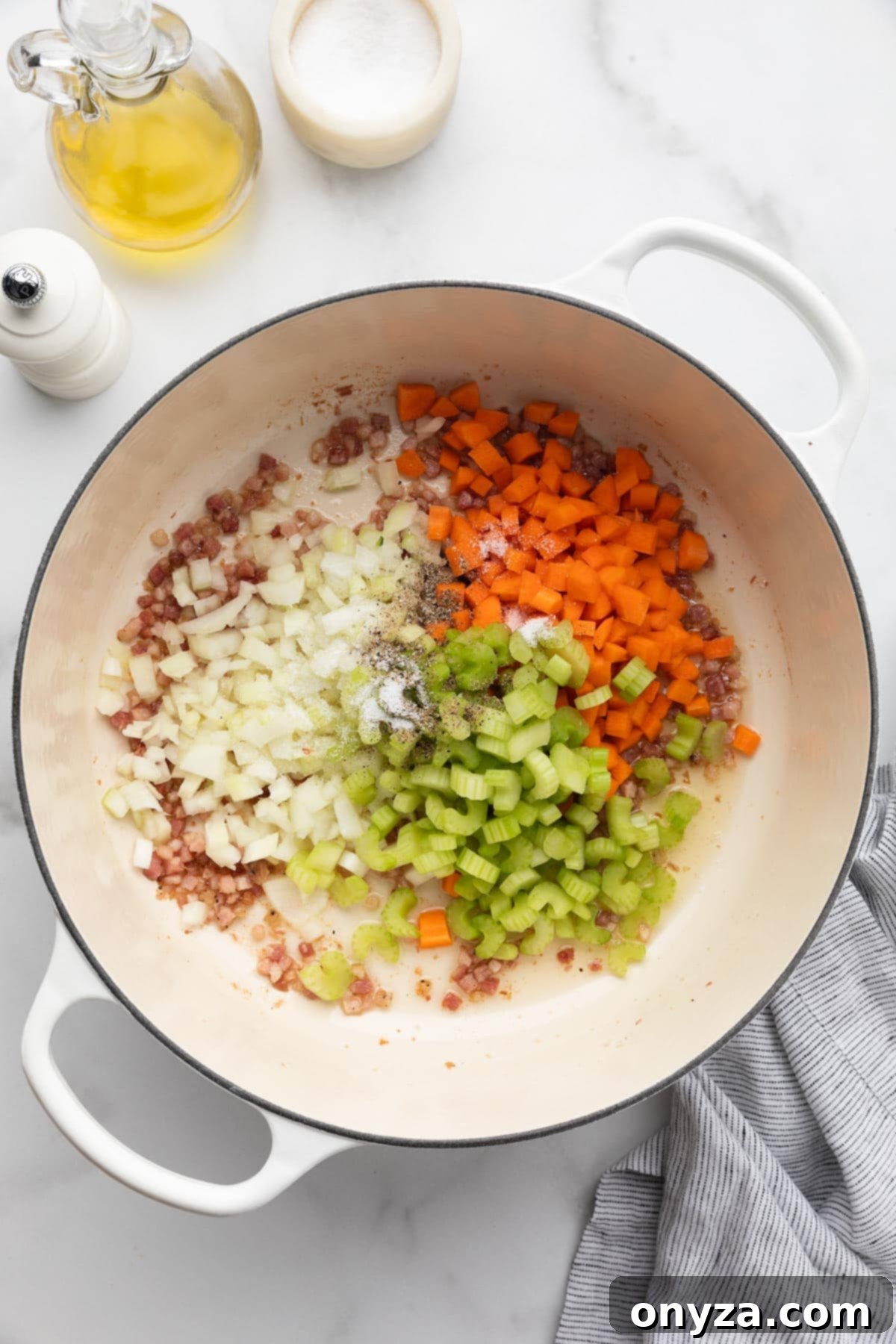 Diced celery, carrots, and onions, known as mirepoix, combined with fried diced pancetta in a white enameled cast iron Dutch oven.