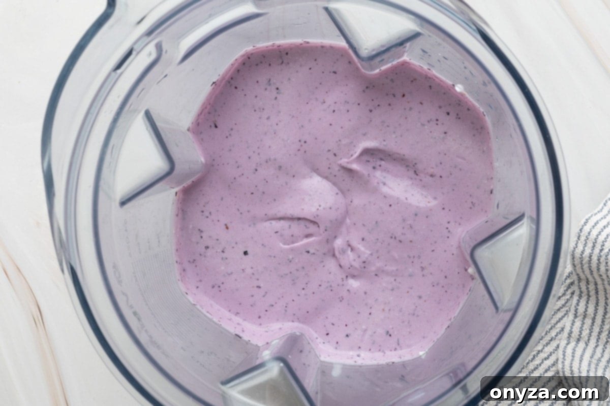 Blueberry Protein Smoothie Bowls 5 A close-up shot of the perfectly blended blueberry cottage cheese mixture inside a blender canister, showcasing its smooth and creamy texture.