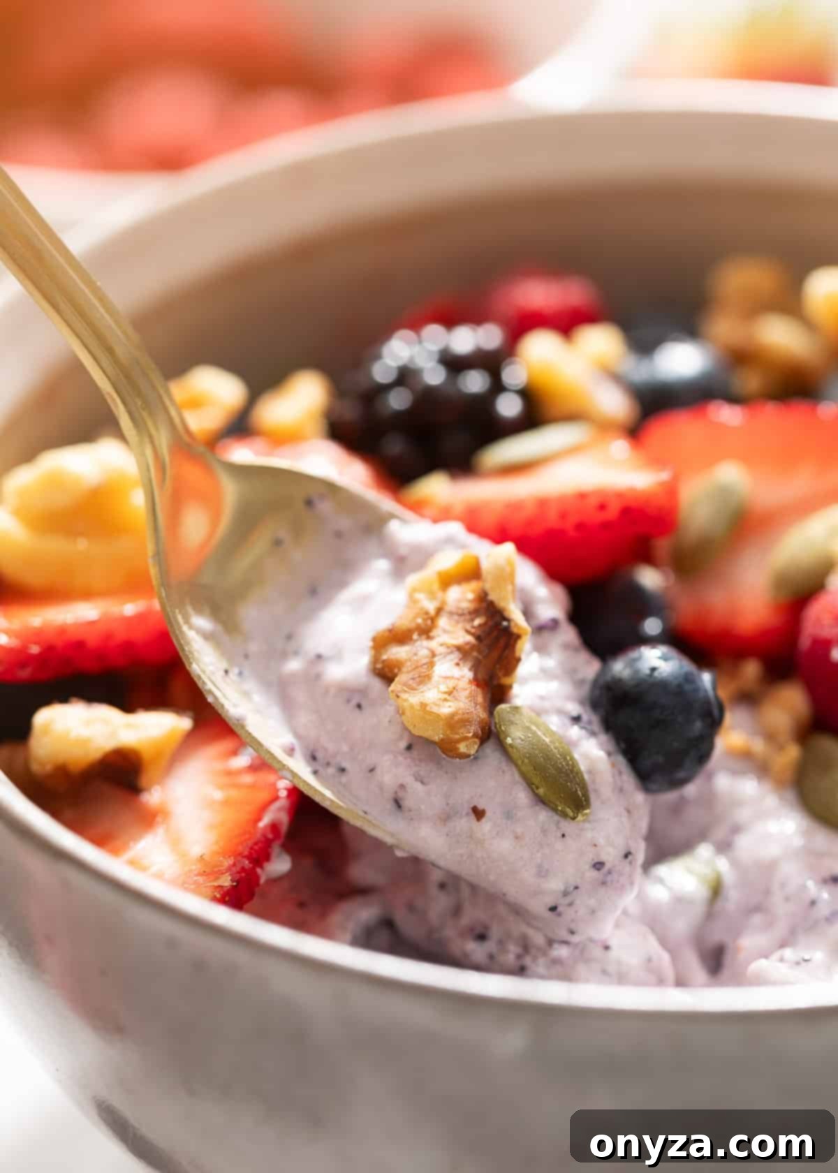 Blueberry Protein Smoothie Bowls 7 A gold spoon is elegantly scooping a portion of the creamy blueberry cottage cheese smoothie bowl, highlighting its luscious texture.