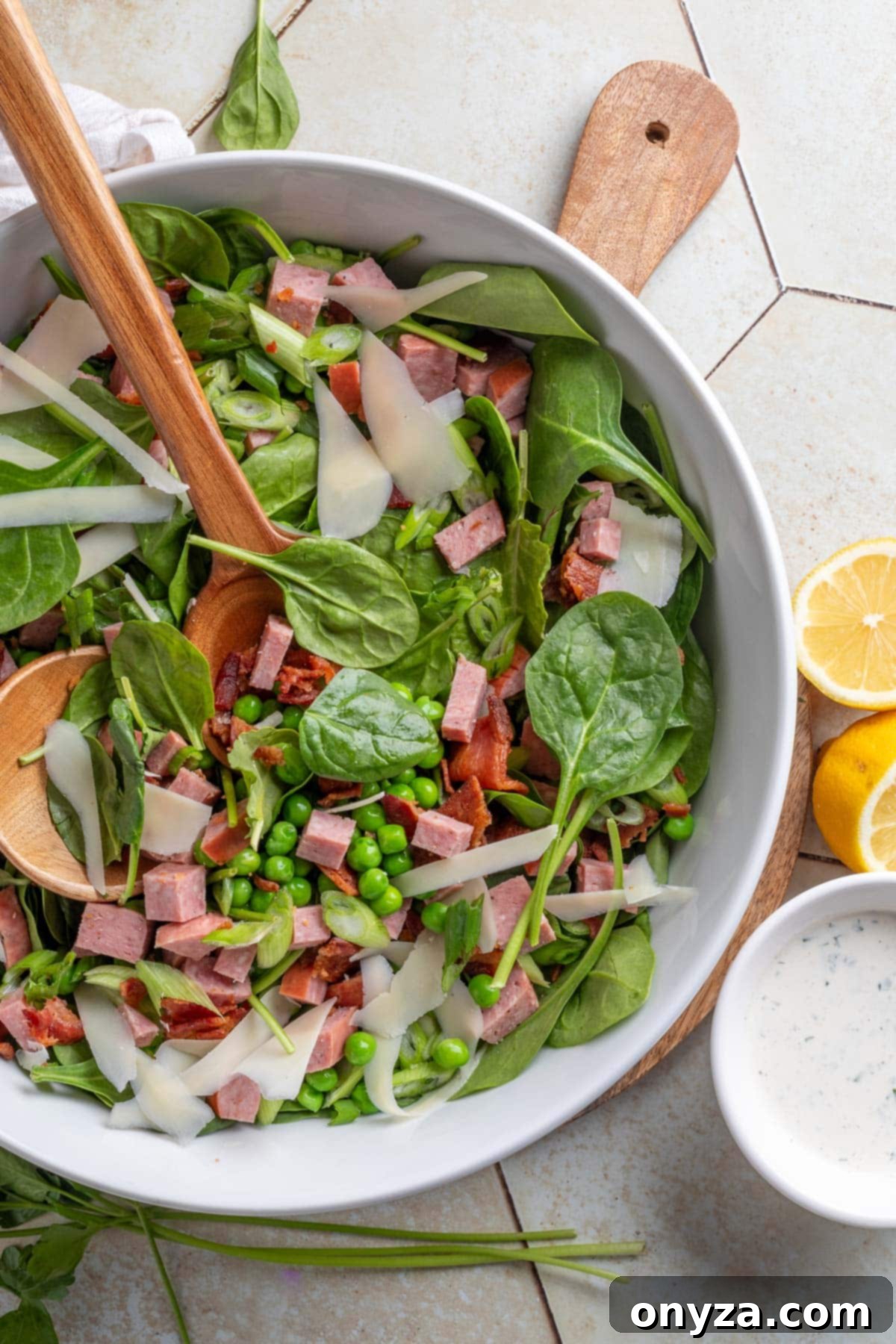 Savory Spinach & Pea Salad with Crispy Bacon and Sausage 2 Spinach and pea salad with summer sausage and bacon in a white bowl on a tile surface, garnished with fresh dill.