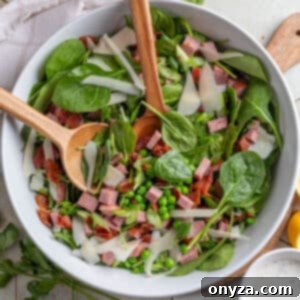 Savory Spinach & Pea Salad with Crispy Bacon and Sausage 13 spinach and pea salad with summer sausage and bacon in a white bowl on a tile surface