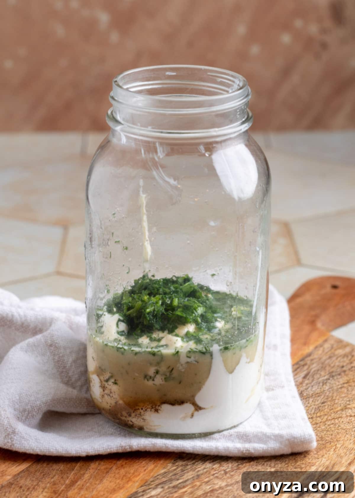 Savory Spinach & Pea Salad with Crispy Bacon and Sausage 4 Ingredients for ranch dressing arranged in small bowls around a mason jar on a wooden board.