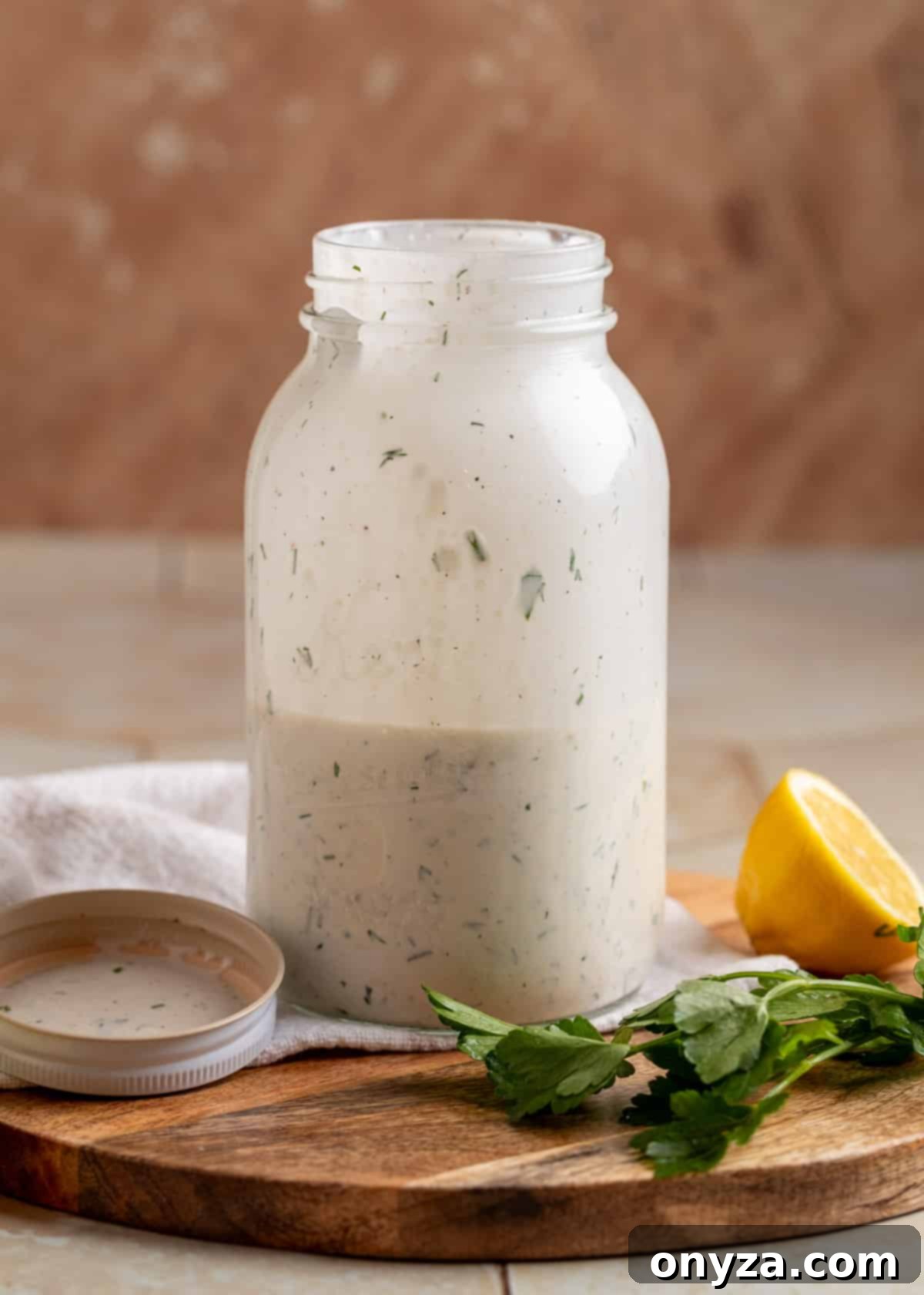 Savory Spinach & Pea Salad with Crispy Bacon and Sausage 5 Dill ranch dressing, perfectly shaken, in a mason jar on a wooden board, with fresh dill and a lemon wedge nearby.