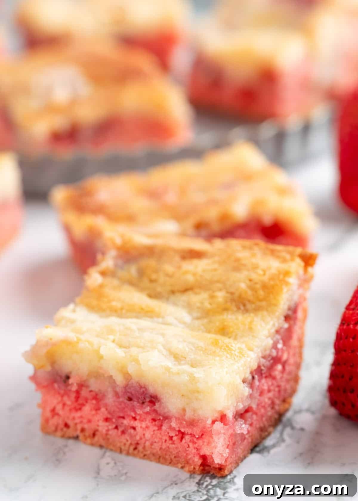 Freshly baked strawberry chess squares arranged neatly on a pristine white marble surface, ready to be served.