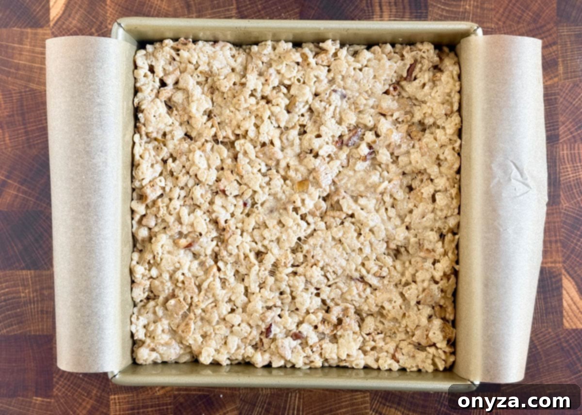 overhead of caramel apple rice krispies treats in a parchment lined square baking pan