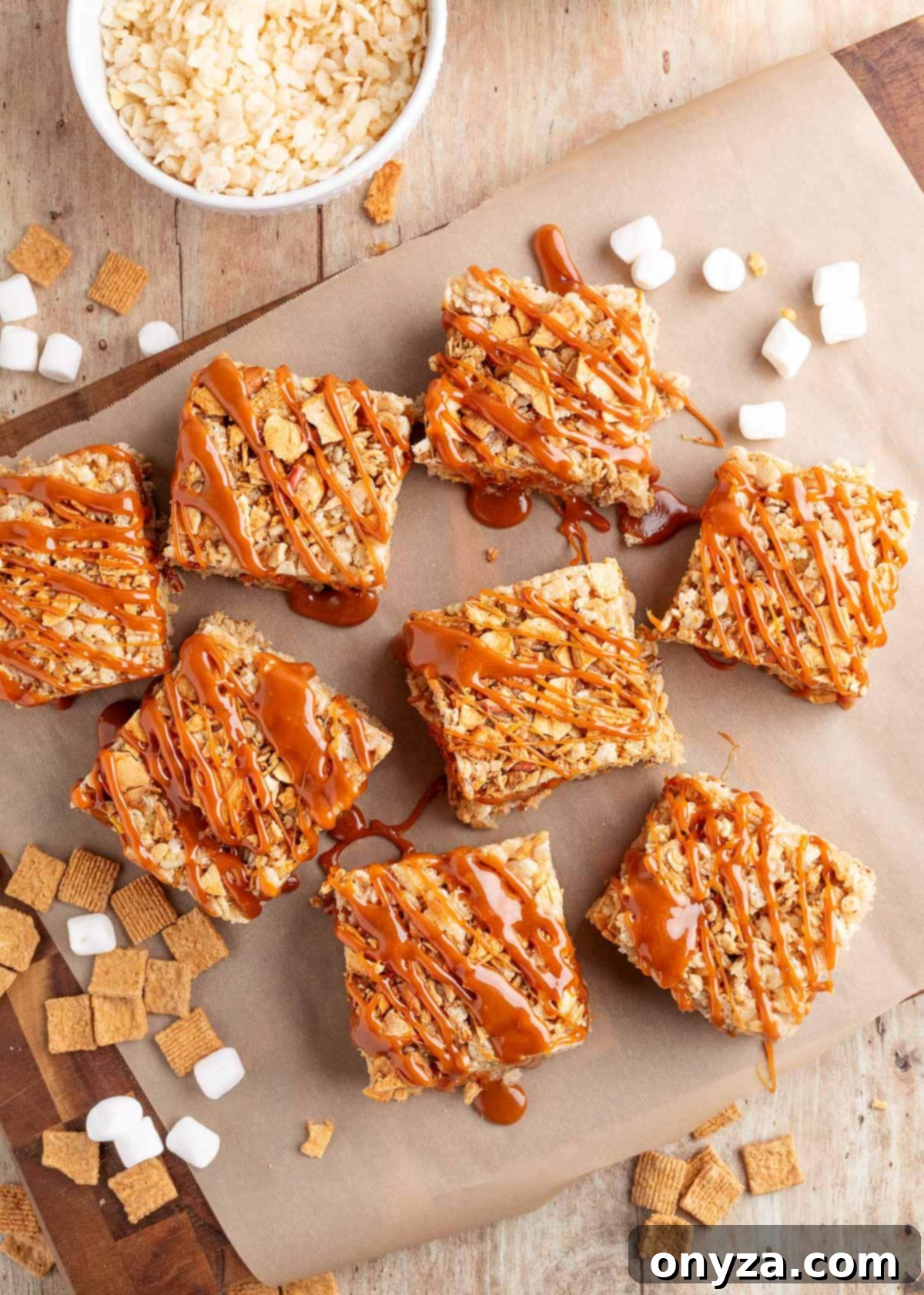 overhead of caramel apple pie rice krispies treats on parchment with marshmallows and golden grahams scattered around